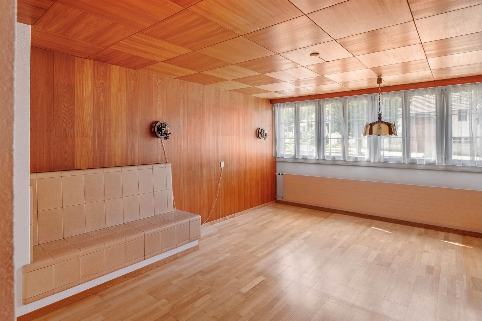 Wohnzimmer mit Holzverkleidung und großem Fenster