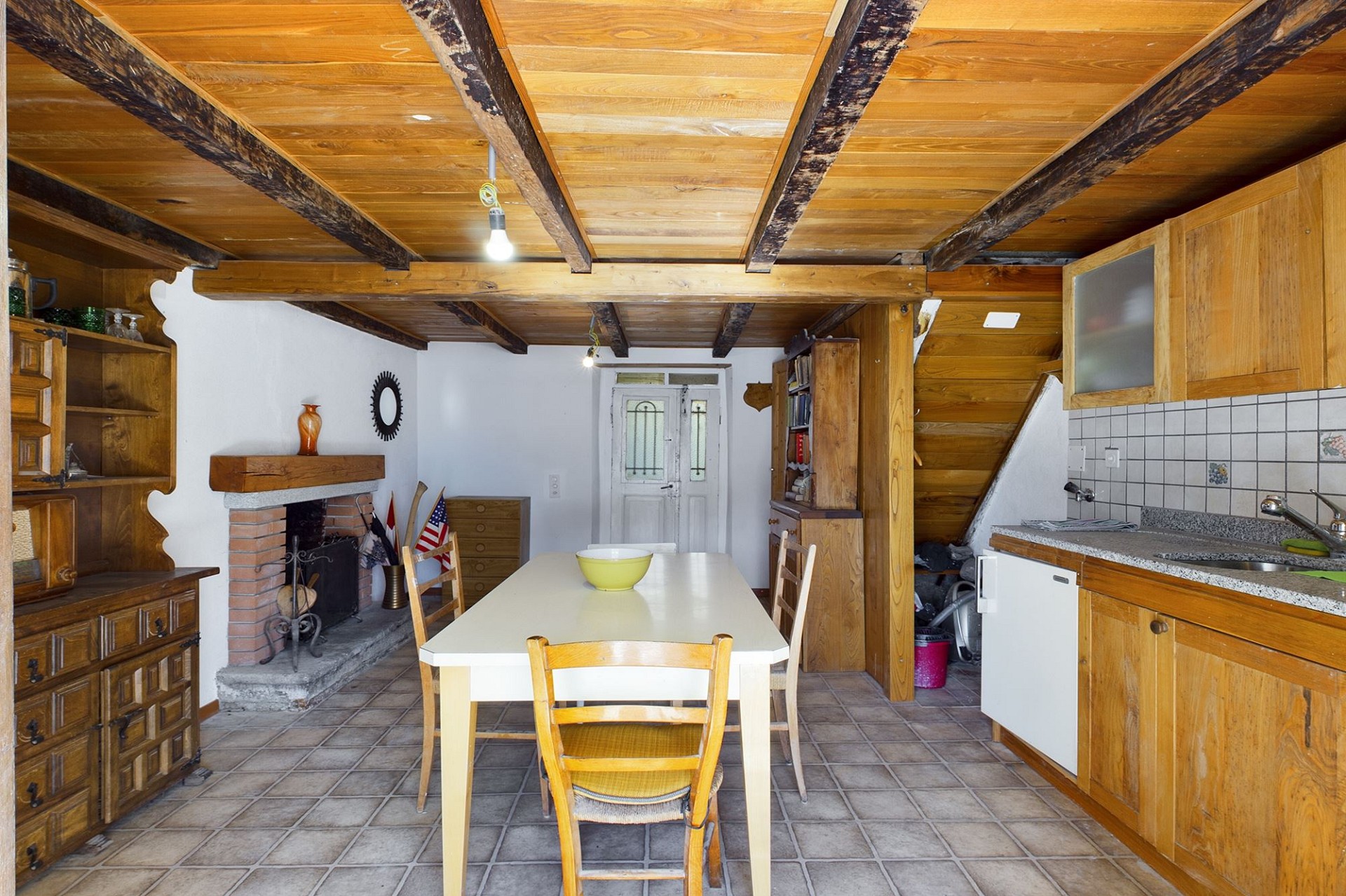 Rustikale Wohnküche mit Kamin und Holzbalkendecke