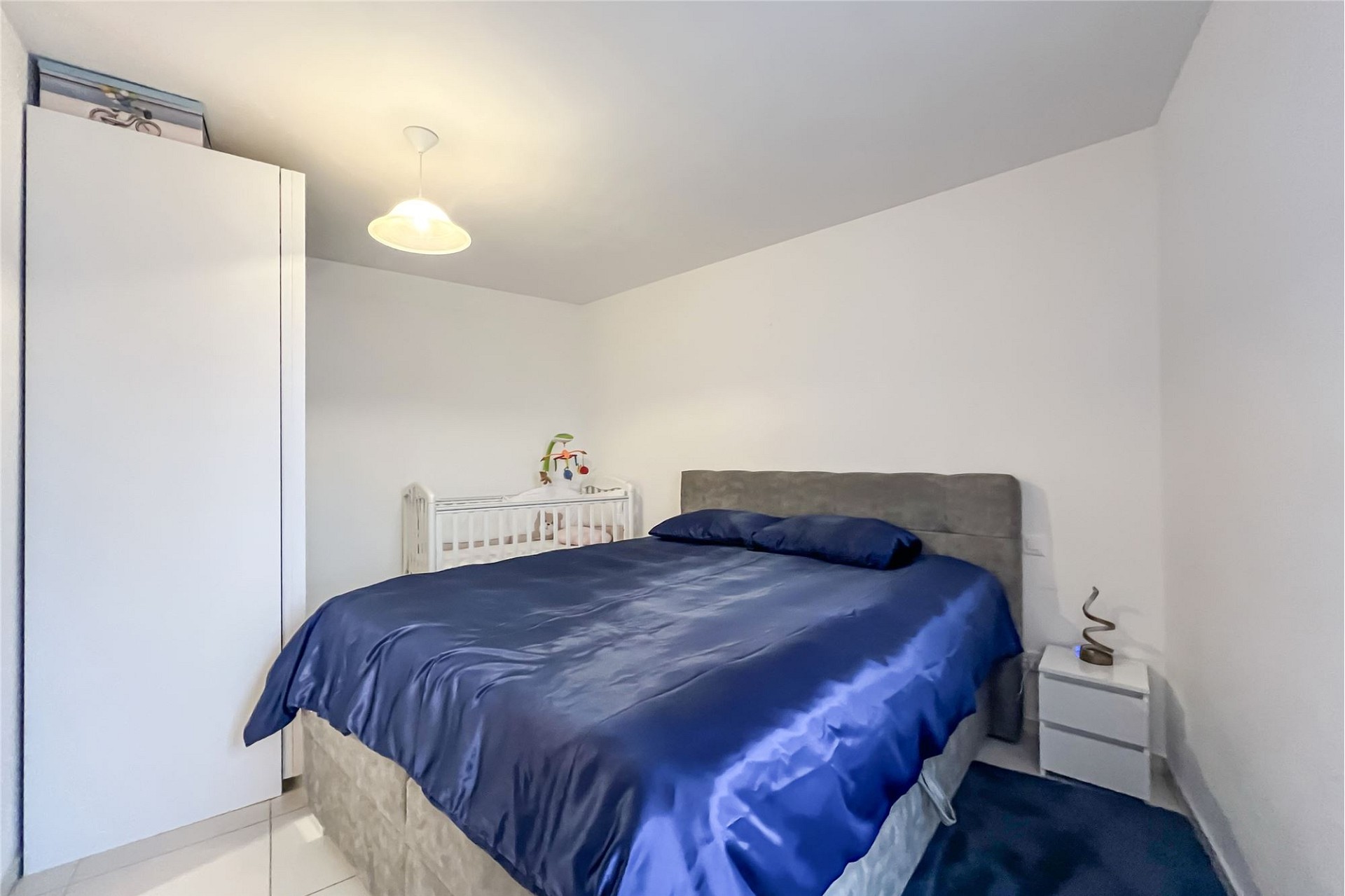 Helles Schlafzimmer mit Kinderbett und großem Bett