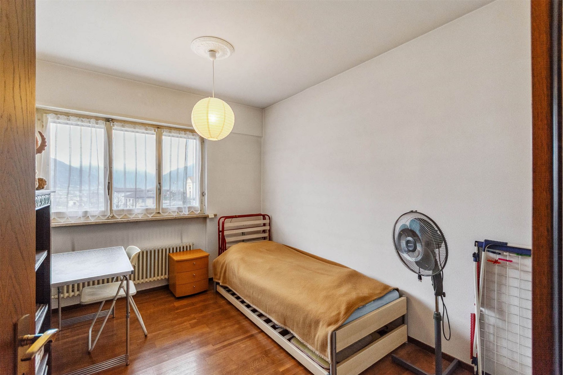 Einfaches Schlafzimmer mit Einzelbett und Blick ins Grüne