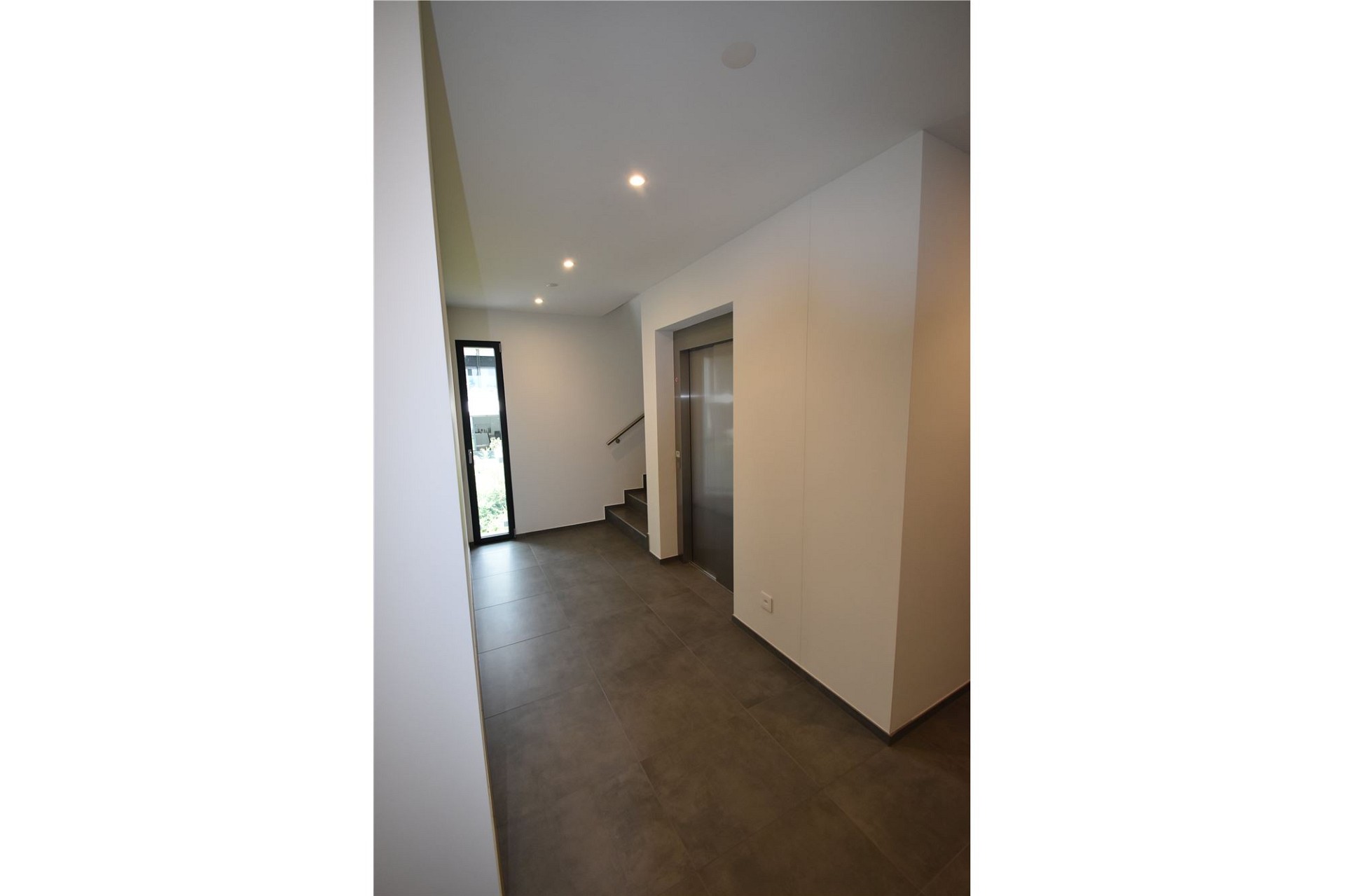 Moderner Eingangsbereich mit Aufzug und Treppe