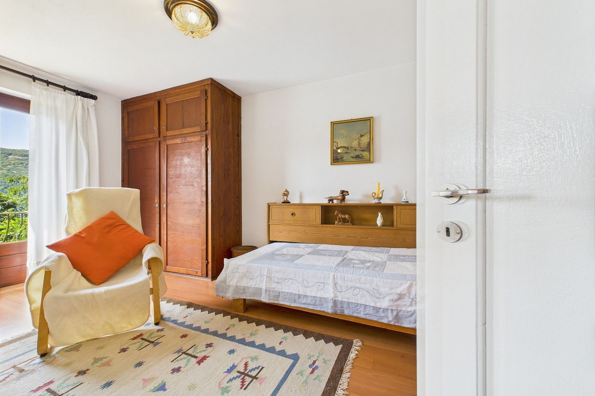 Helles Schlafzimmer mit Holzmöbeln und Balkonblick