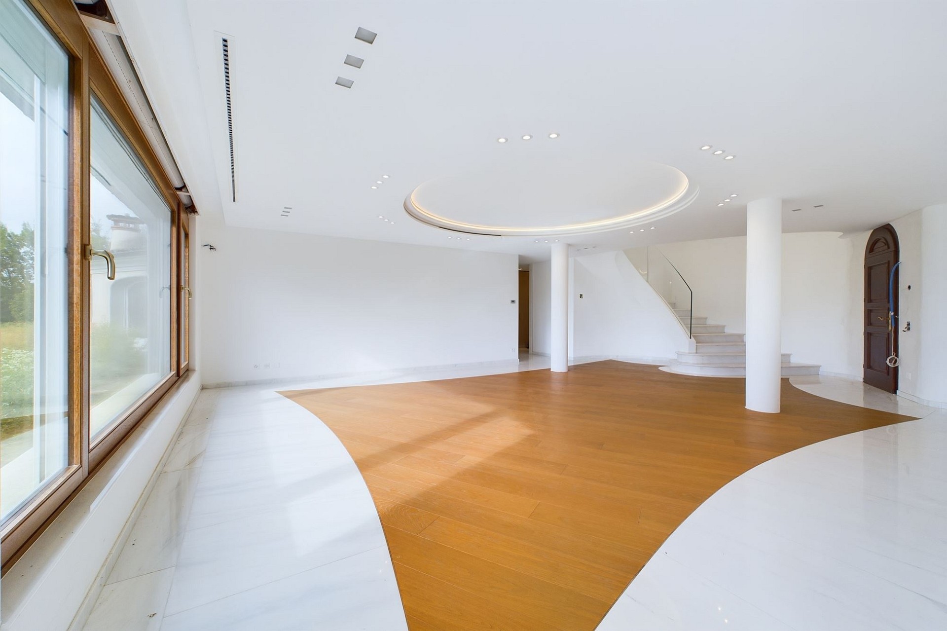 Großzügiger, leerer Wohnraum mit Treppe und Rundfenster