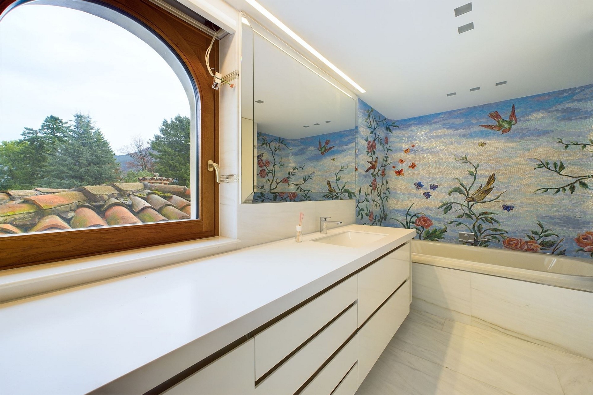 Helles, luxuriöses Badezimmer mit Fenster und Mosaikwand