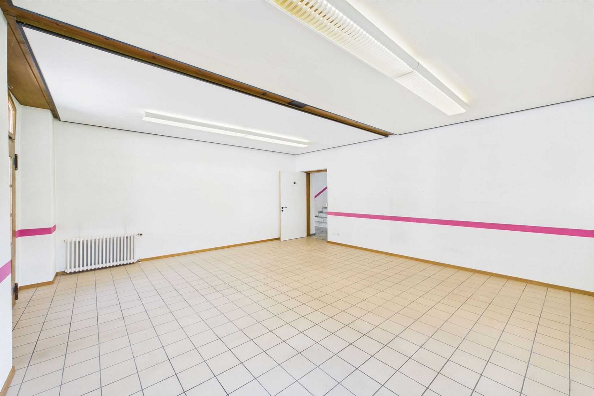 Heller leerer Raum mit Fliesenboden und Treppe im Hintergrund
