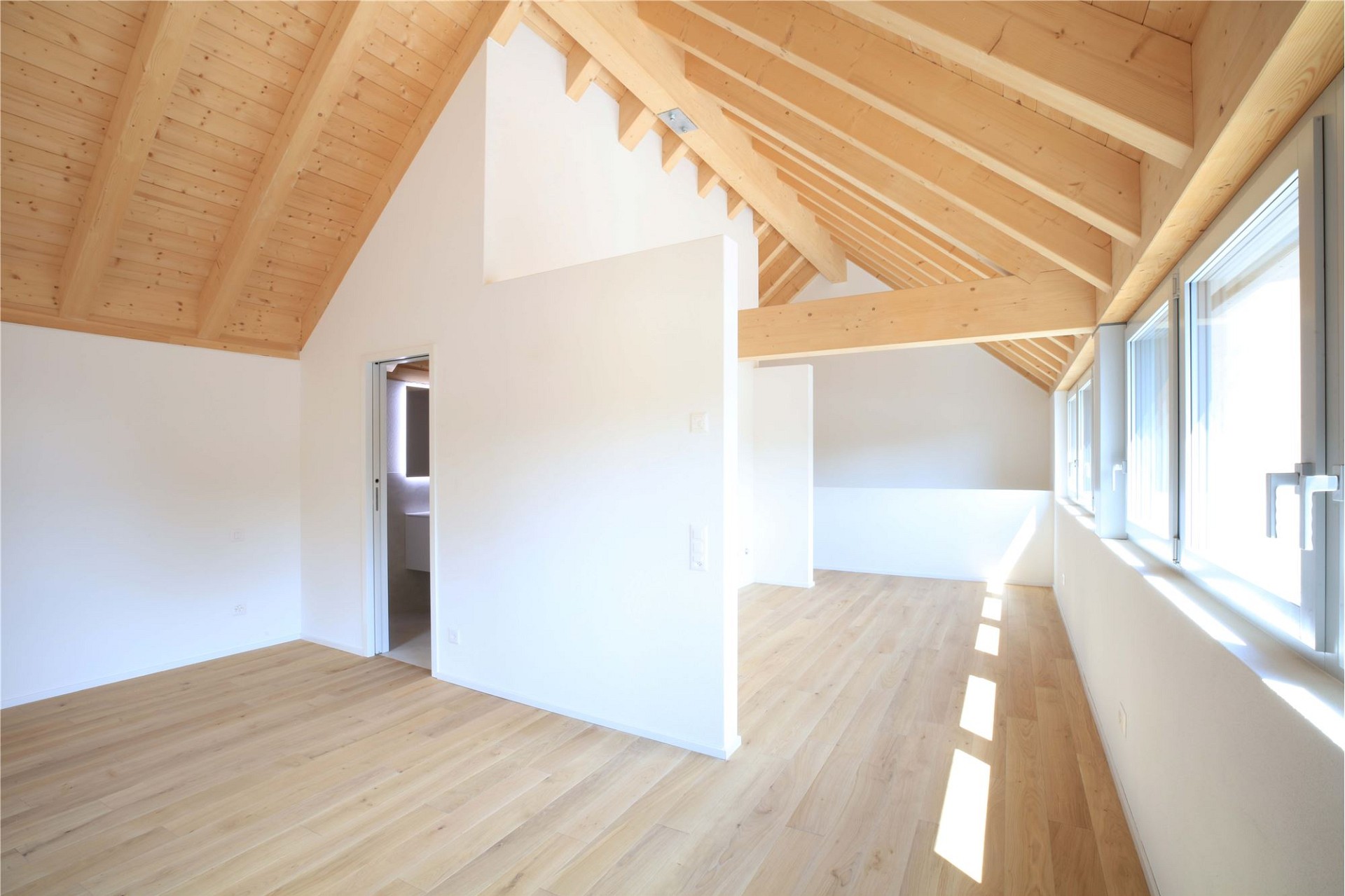 Heller Dachgeschossraum mit sichtbaren Holzbalken