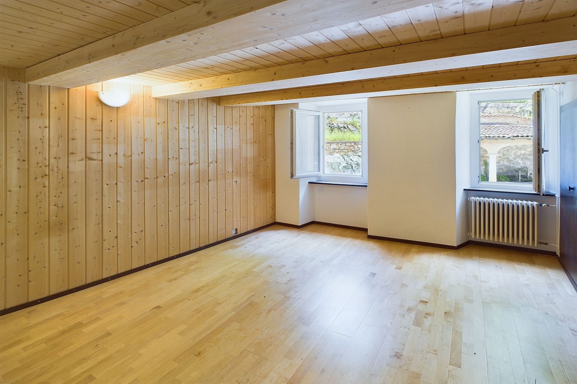 Leerer, holzvertäfelter Raum mit zwei Fenstern