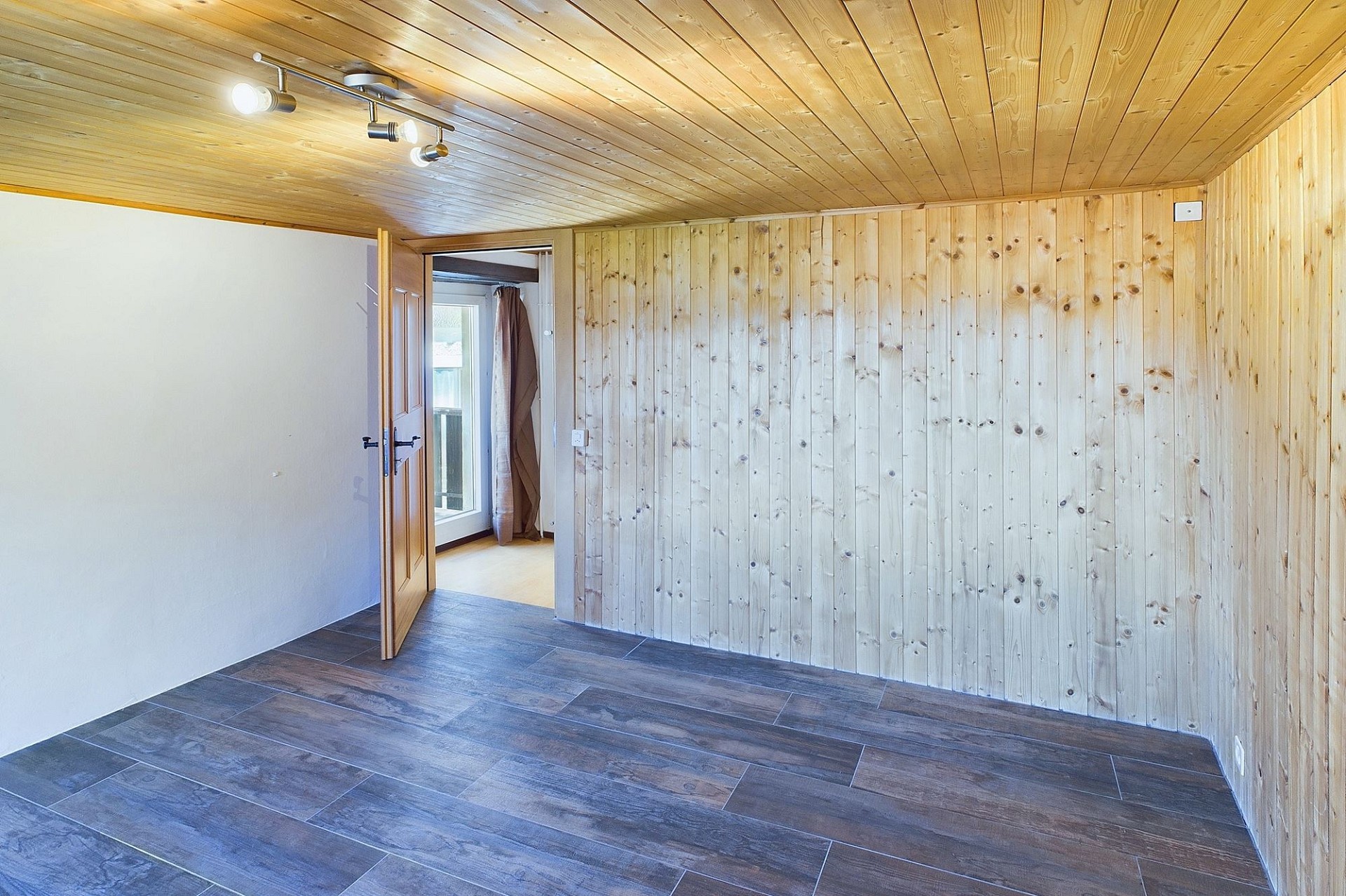 Holzverkleideter Raum mit dunklem Fliesenboden
