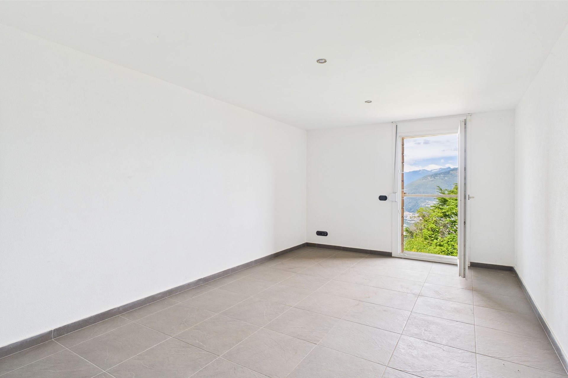 Leerer heller Raum mit Balkon- oder Terrassentür und Bergblick