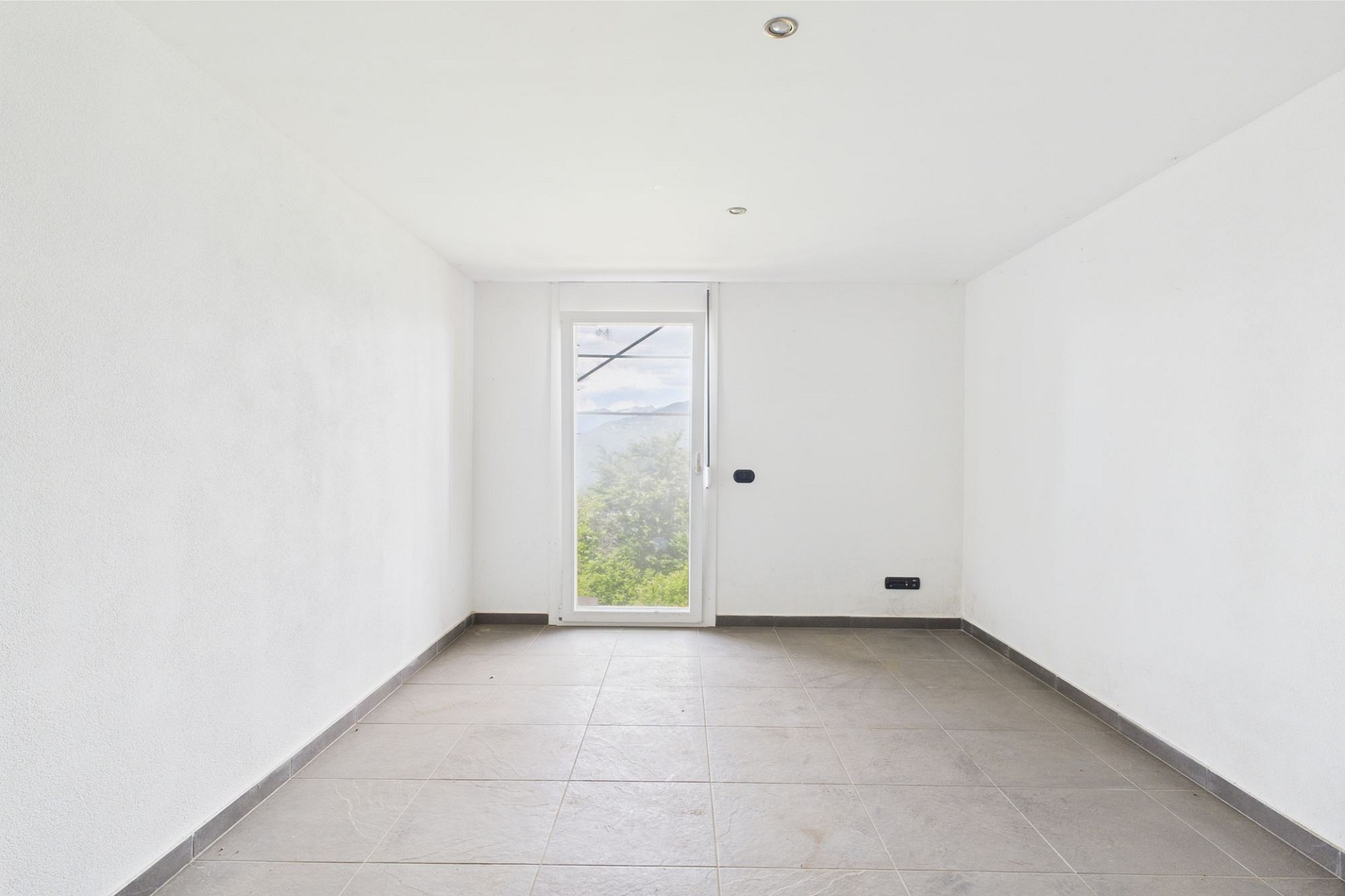 Leerer heller Raum mit Fenster und Fliesenboden