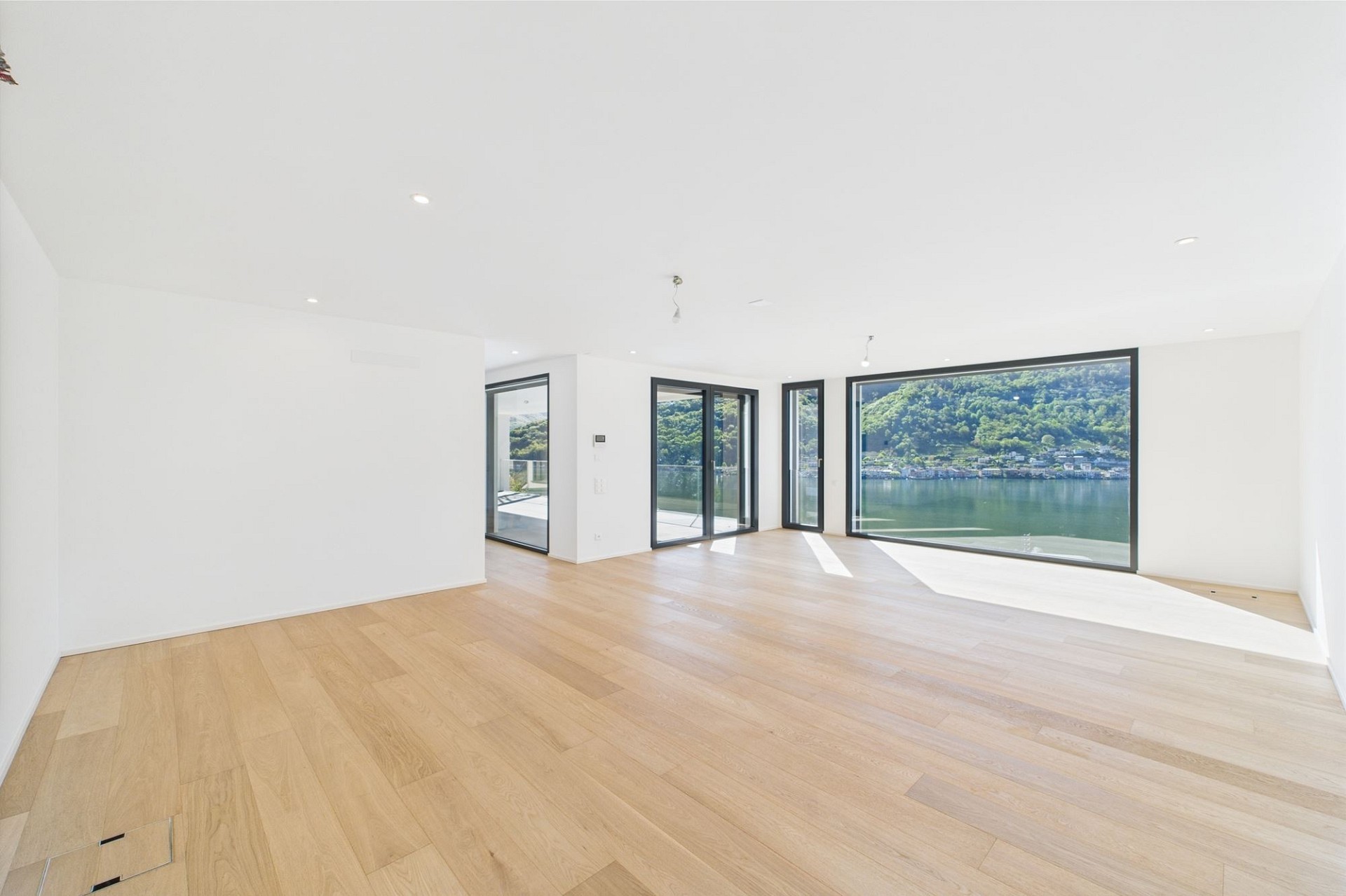 Heller, leerer Wohnraum mit Panoramafenstern und Seeblick