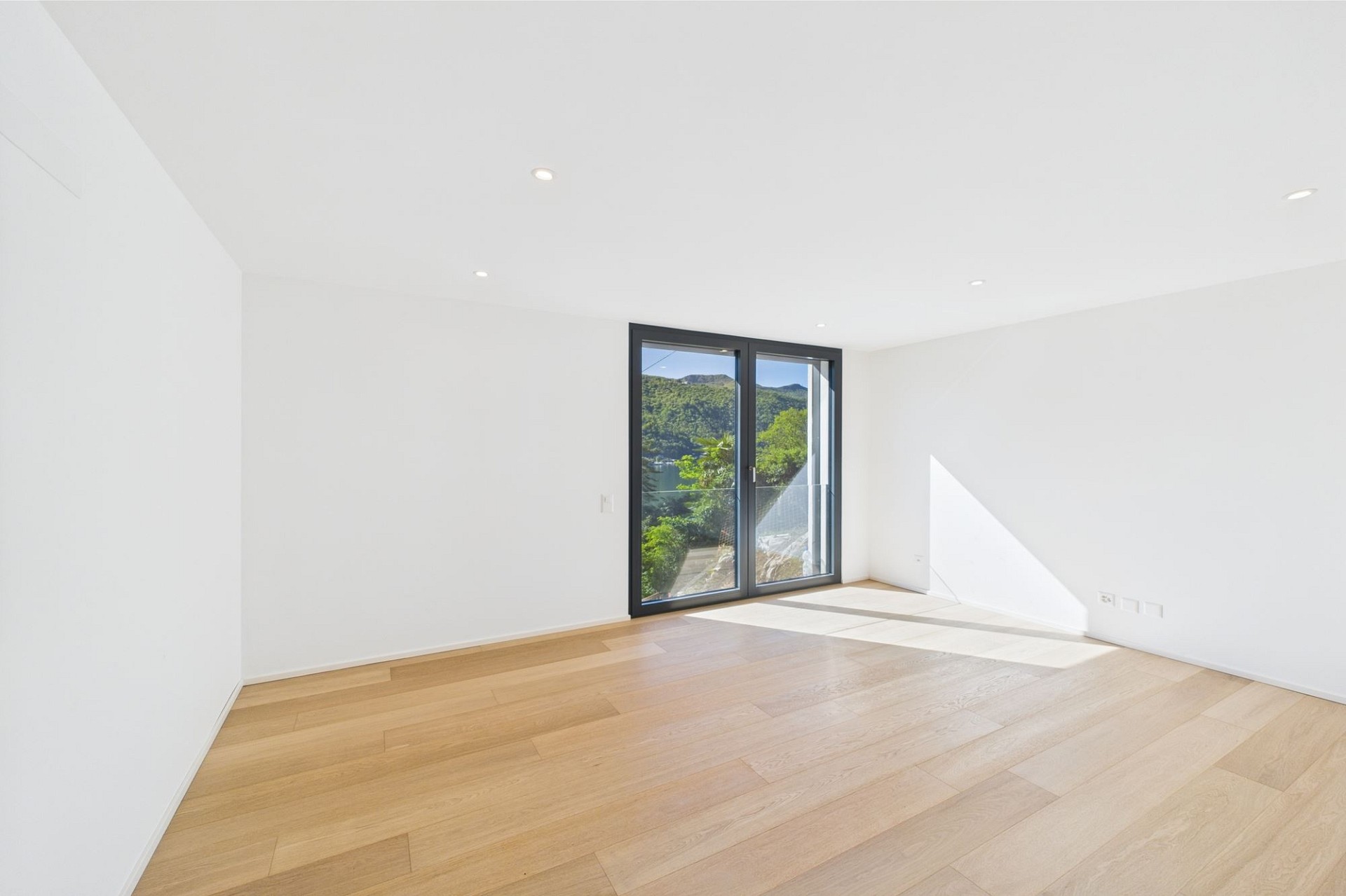 Heller leerer Raum mit Balkon- bzw. Terrassentür und Bergblick