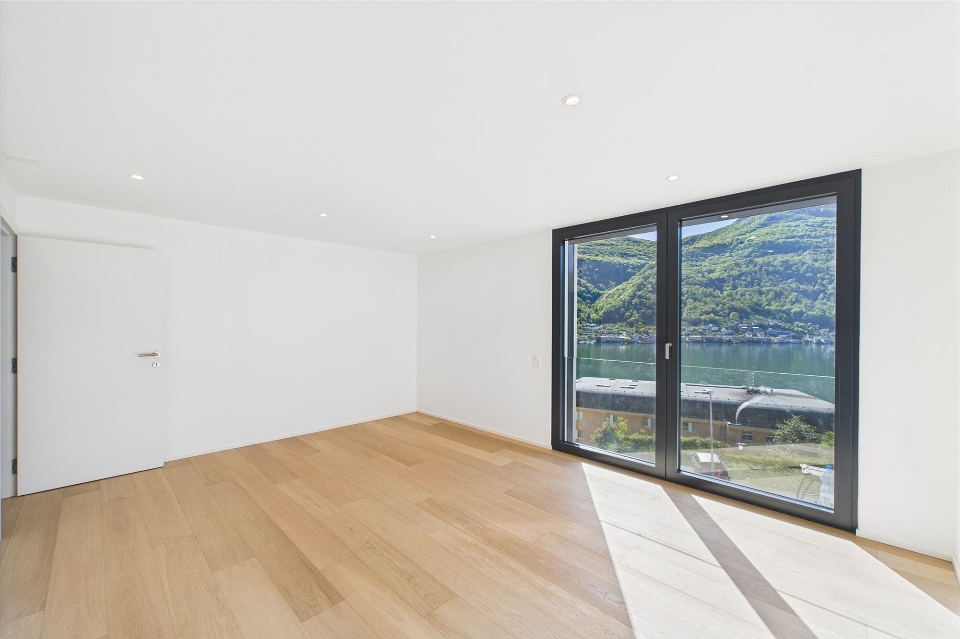 Helles, leeres Zimmer mit Panoramafenster und Seeblick