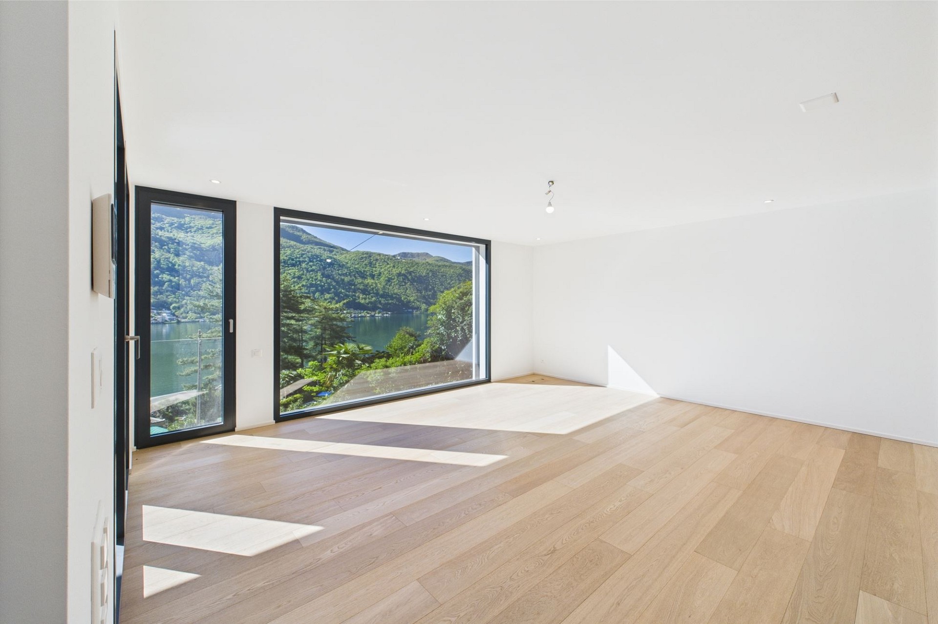 Heller, leerer Wohnraum mit Panoramafenster und Seeblick