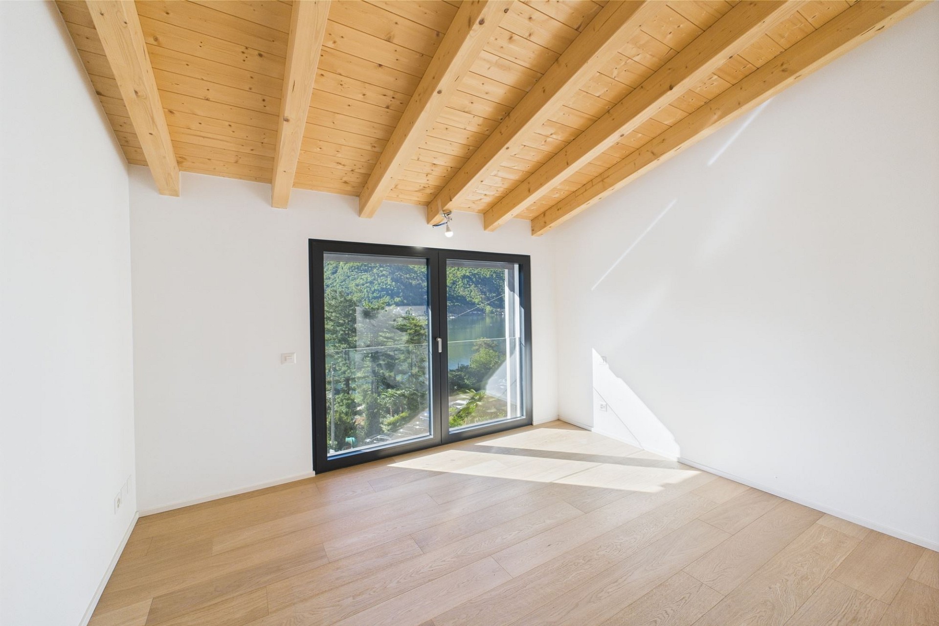 Helles Zimmer mit Holzbalkendecke und Blick ins Grüne