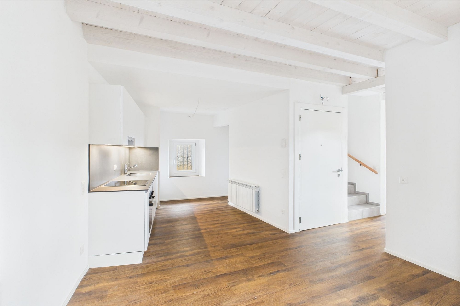 Heller Wohnraum mit offener Küche und sichtbarer Treppe