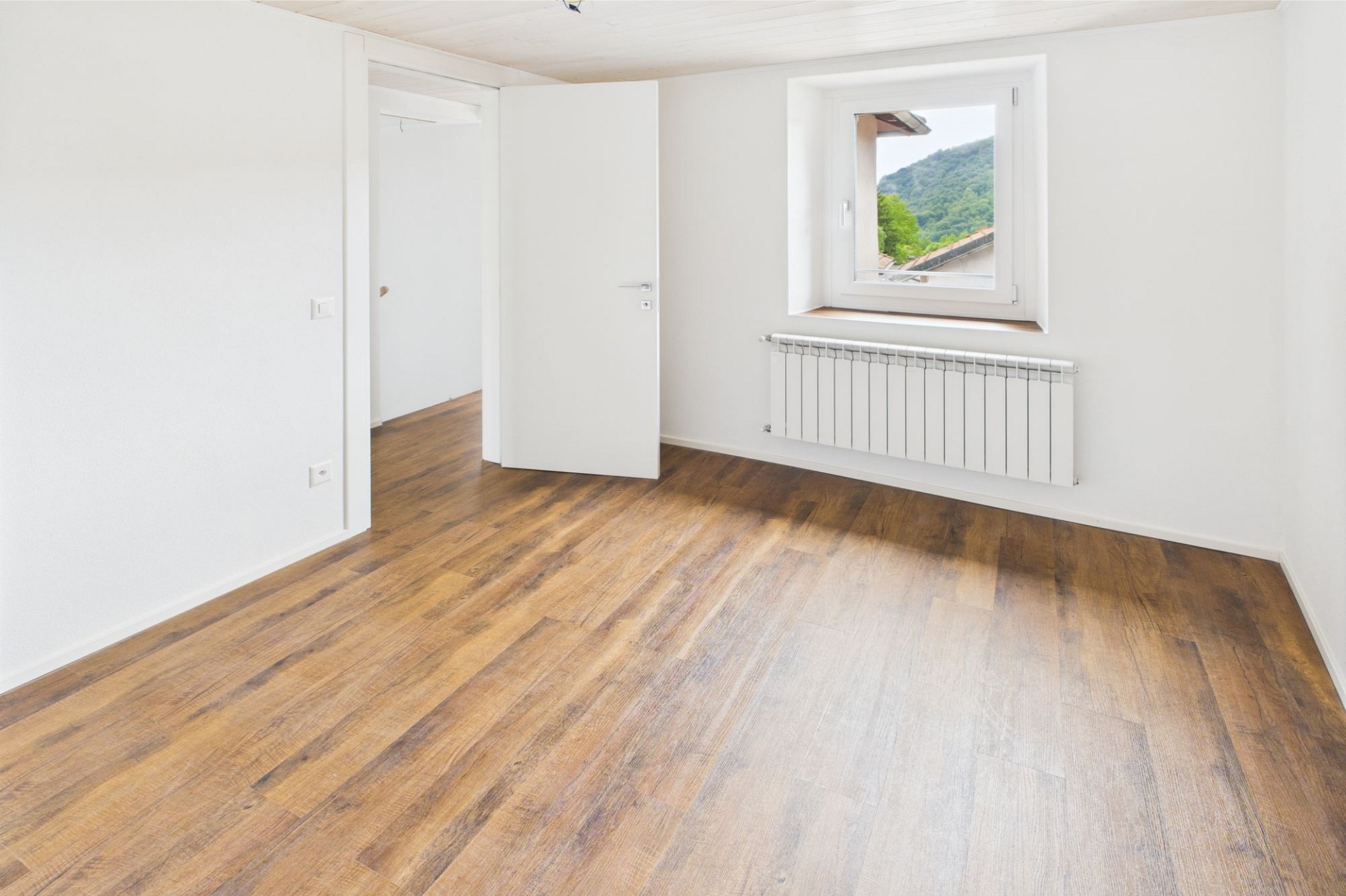 Helles, leeres Zimmer mit Holzoptikboden