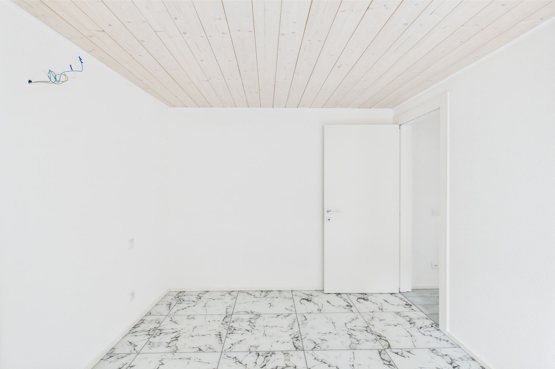 Leerer heller Raum mit Fliesenboden und Holztäfelung an der Decke