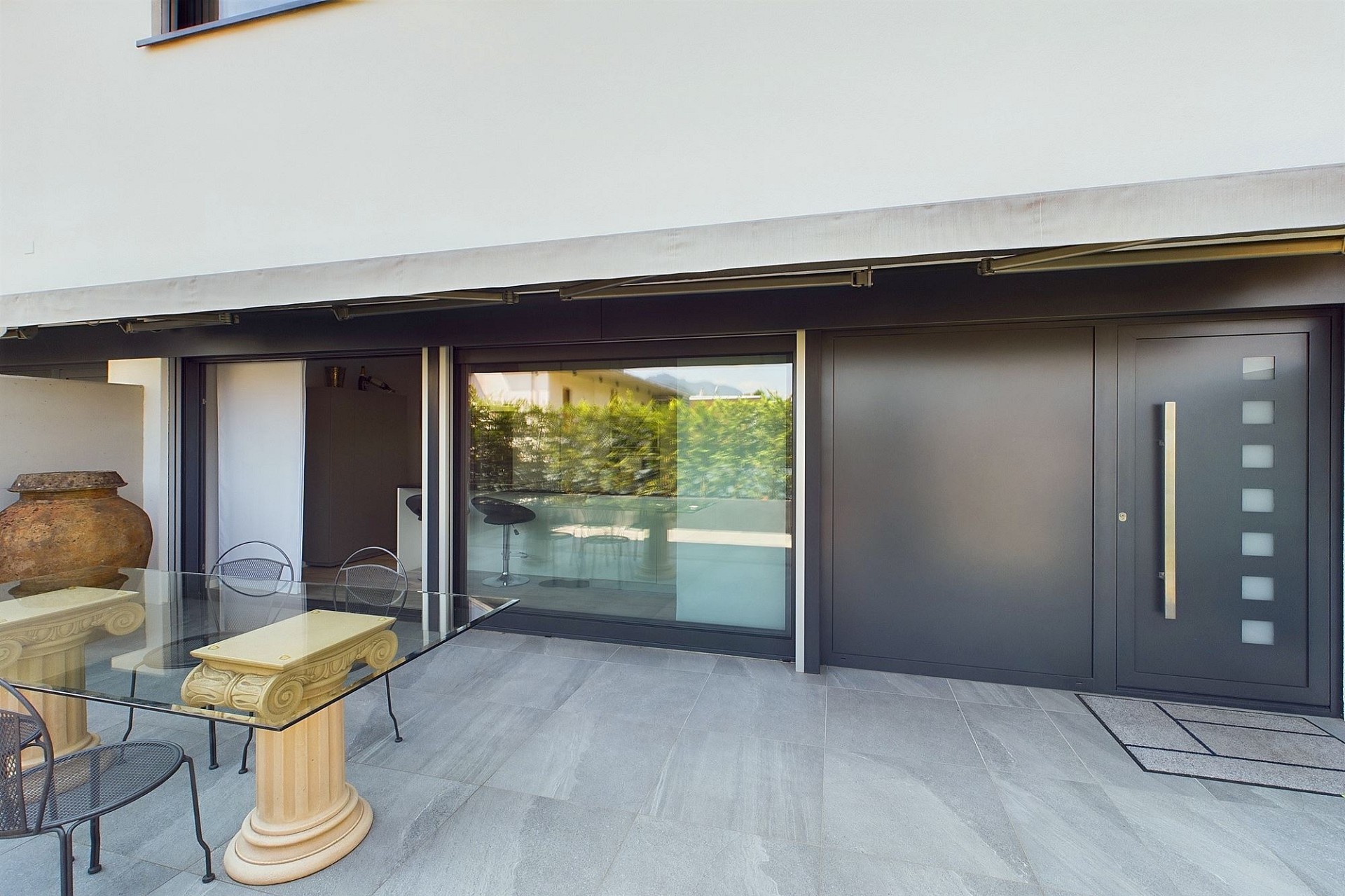 Moderne überdachte Terrasse mit großflächigen Schiebetüren