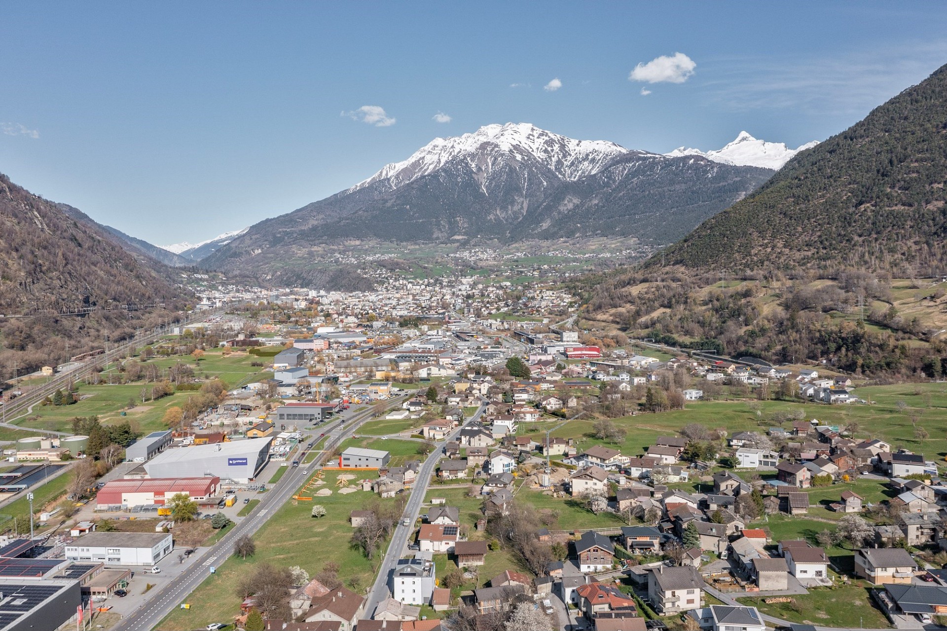 Luftaufnahme eines alpinen Tals mit Stadt und Bergen