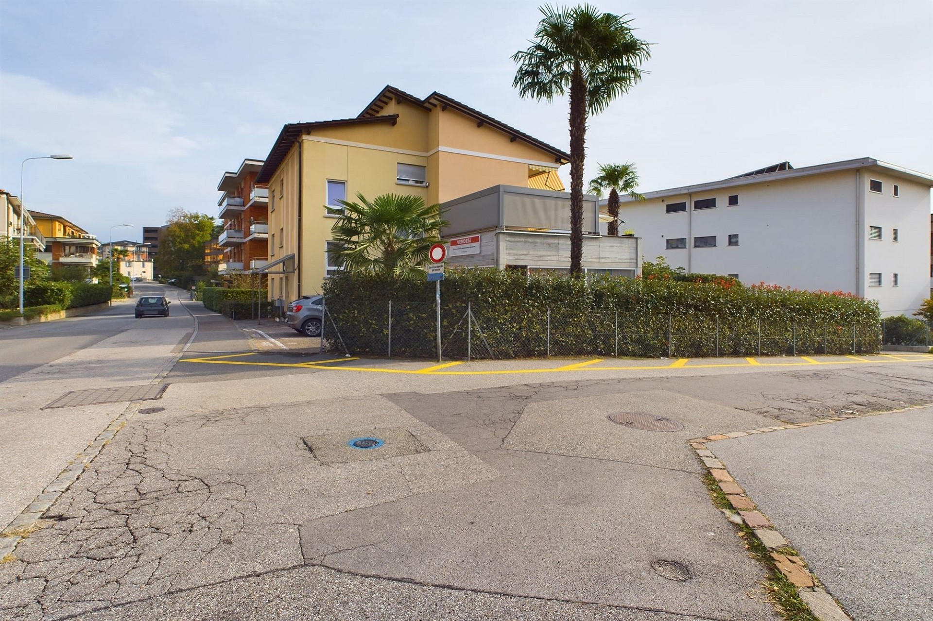 Straßenansicht eines Wohngebäudes mit Balkon und Palmen