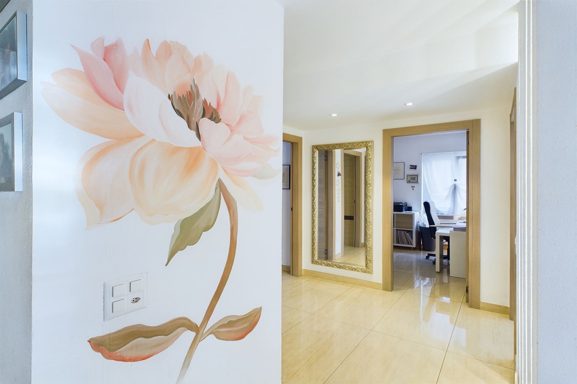 Heller Flur mit Blumenwand und Blick in ein Arbeitszimmer