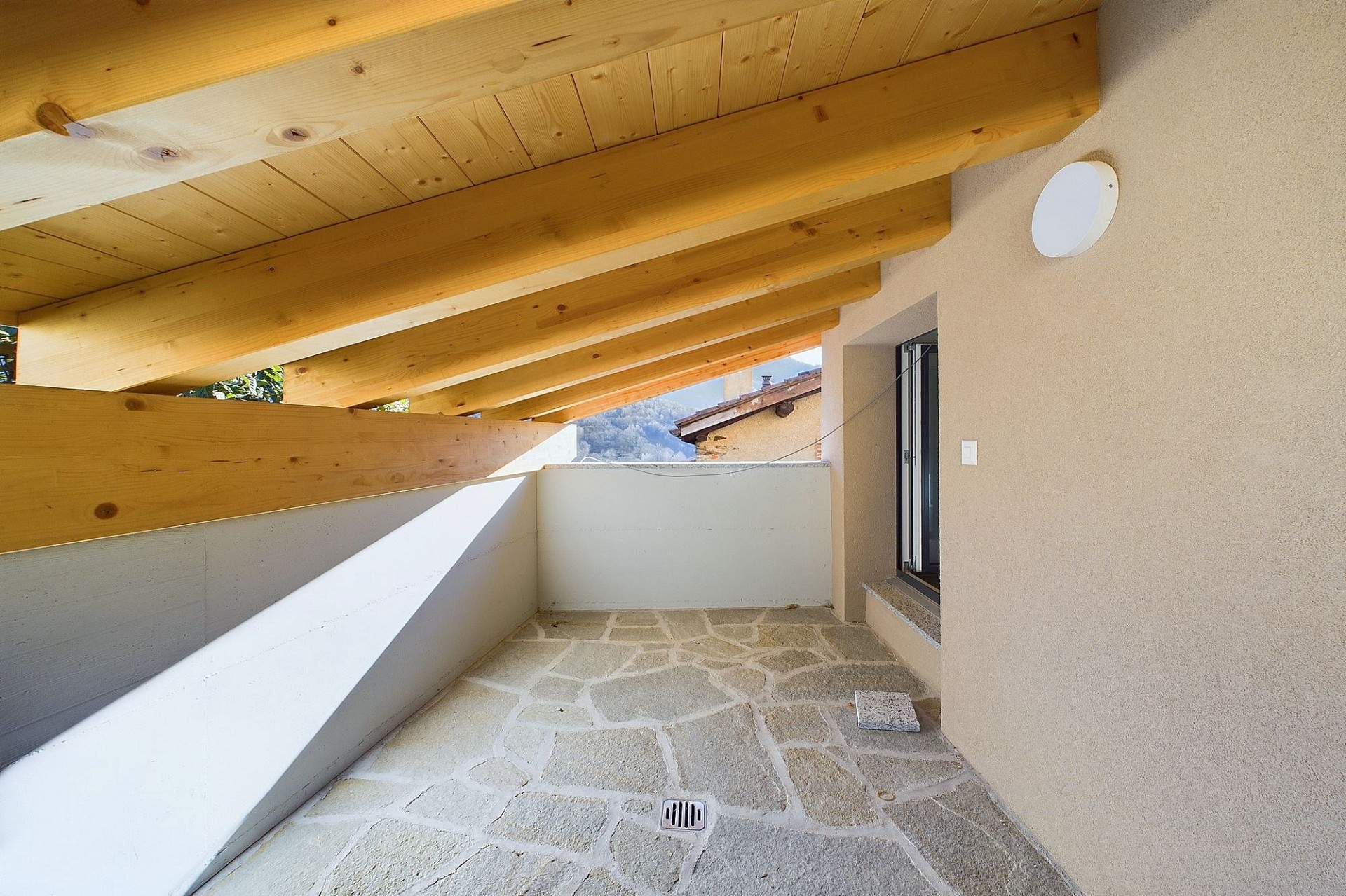 Überdachter Balkon mit Holzbalken und Natursteinboden