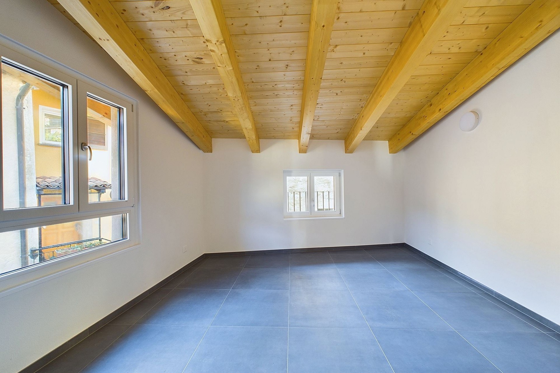 Heller leerer Raum mit sichtbarer Holzbalkendecke