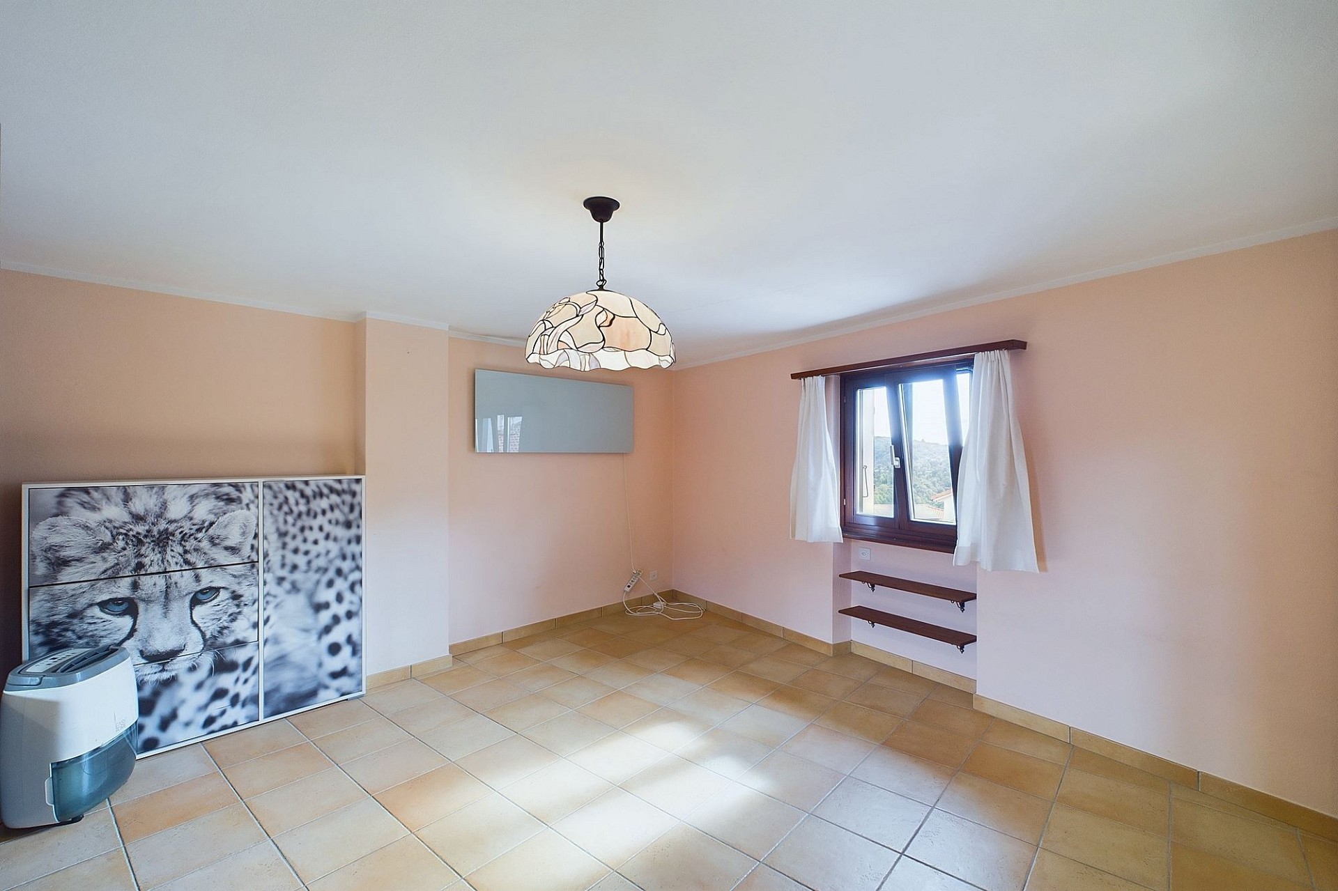 Leerer Wohnraum mit Fliesenboden und Fenster
