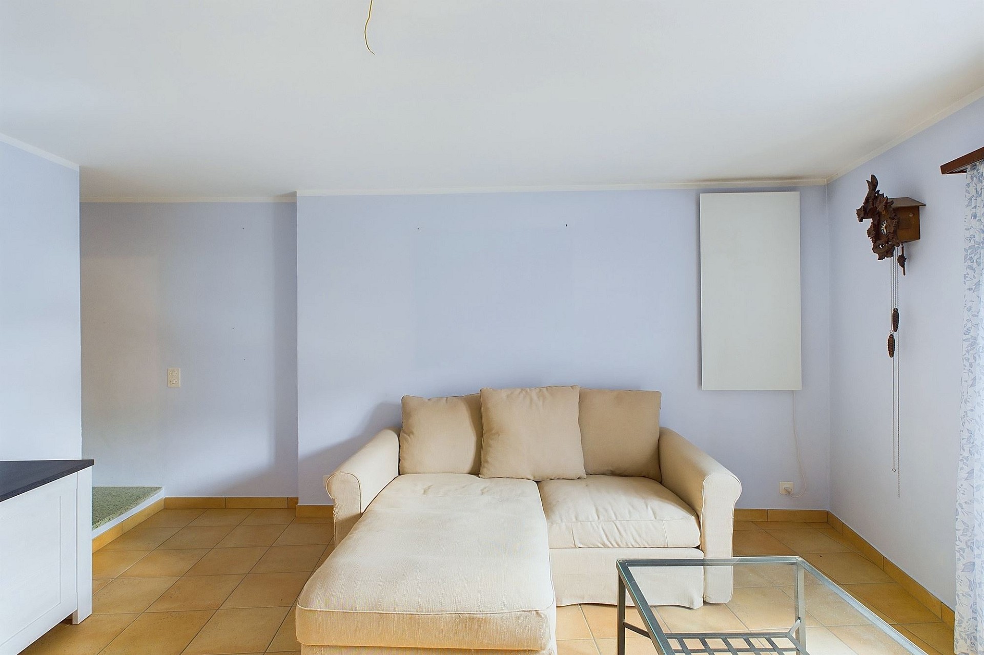 Helles Wohnzimmer mit Sofa und Fliesenboden