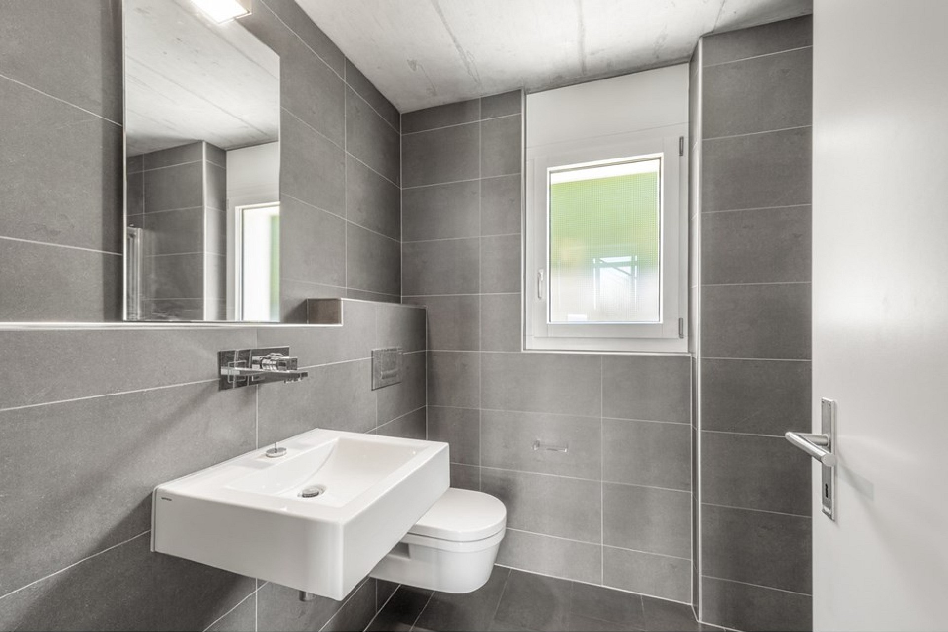 Modernes Bad mit grauen Fliesen und wandhängendem WC
