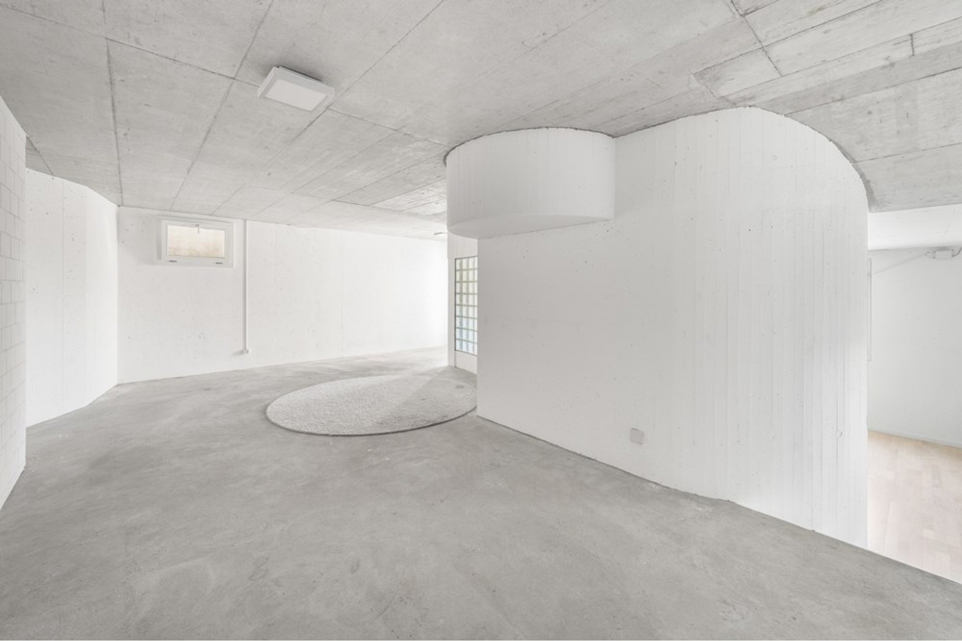 Heller Keller- oder Untergeschossraum mit Sichtbeton und weiß lackierten Wänden