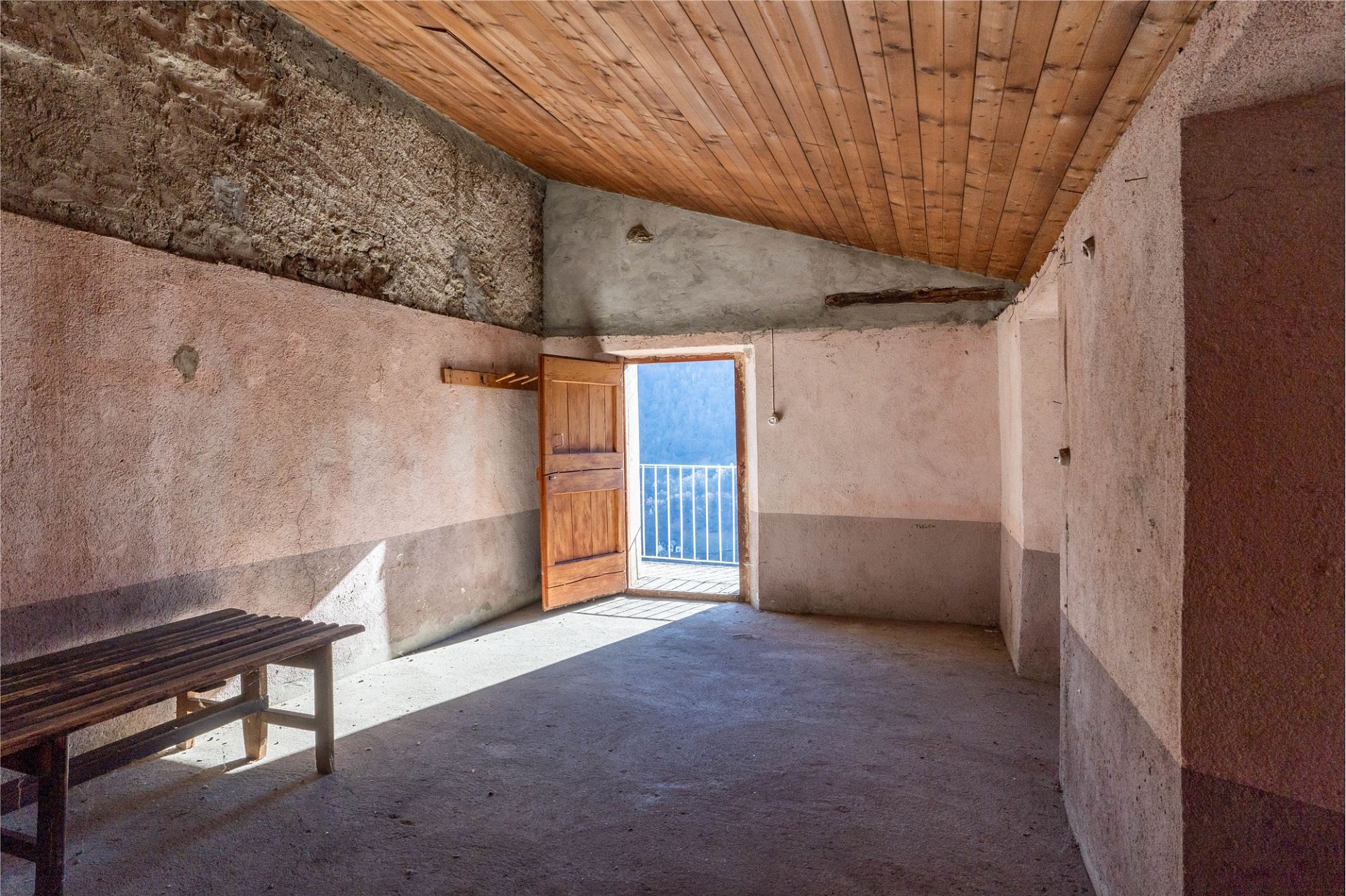 Rustikaler, leerer Innenraum mit Holztür zum Balkon