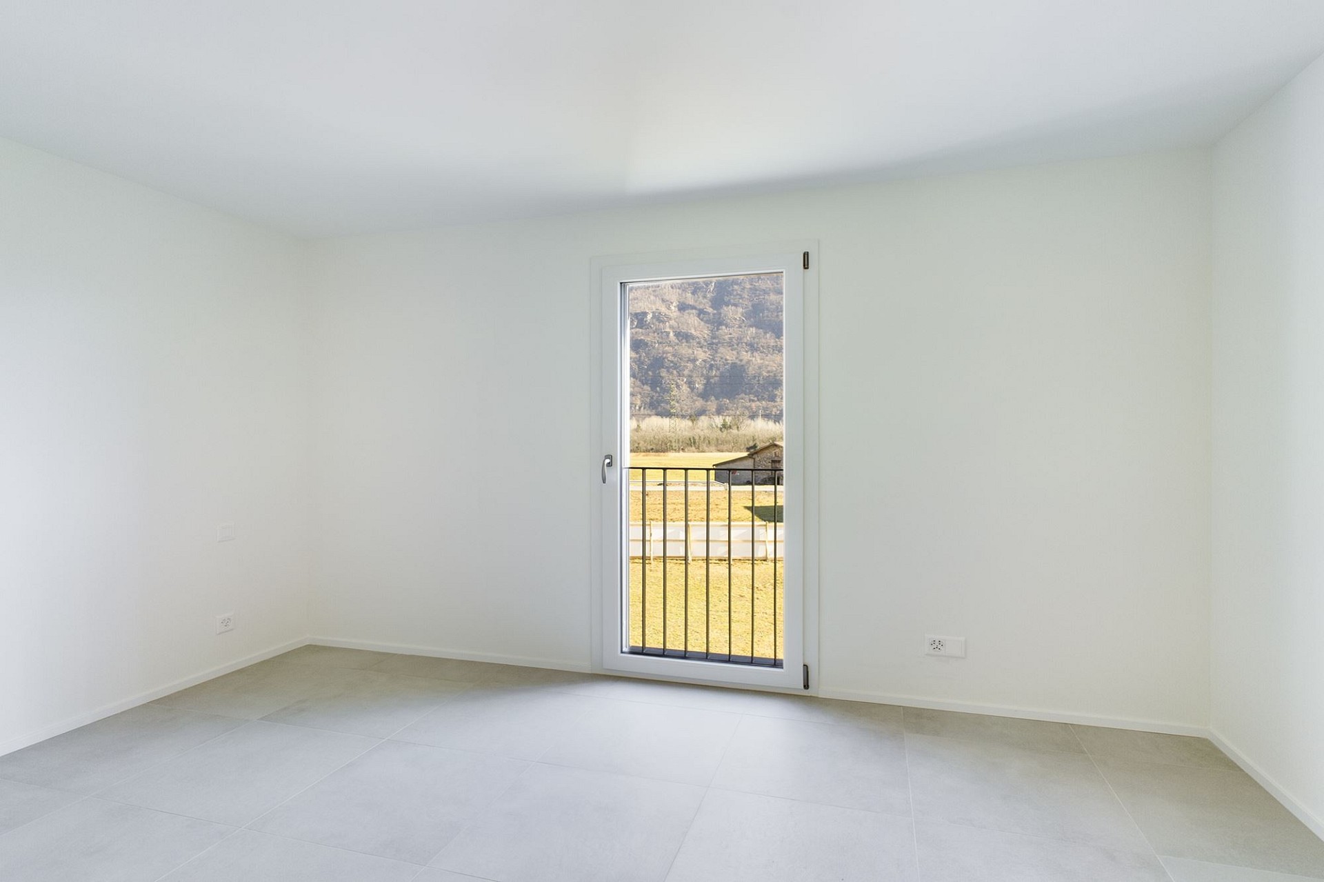 Leerer heller Raum mit Fenstertür und Blick ins Grüne