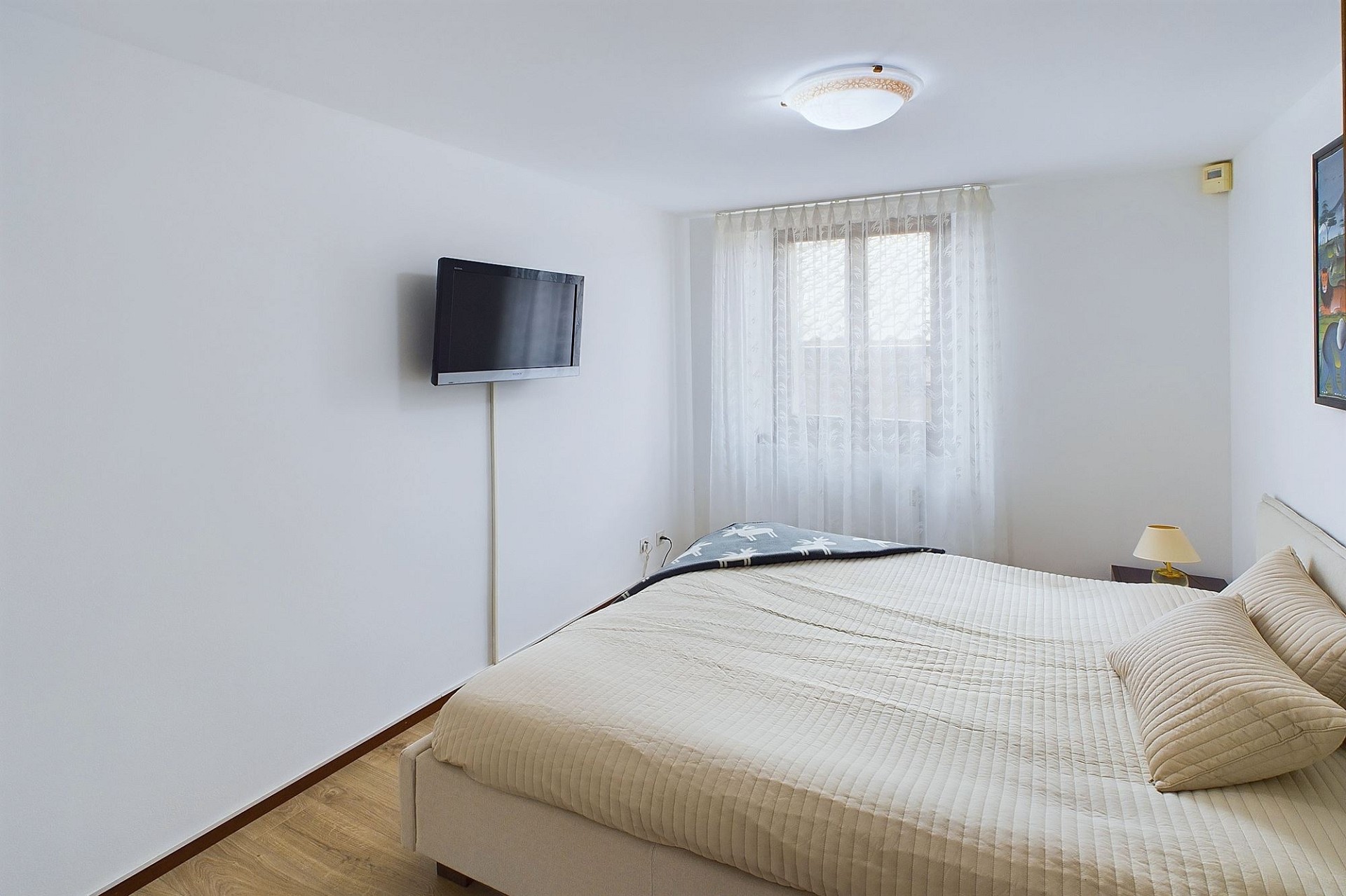 Schlafzimmer mit schlichtem Doppelbett und TV