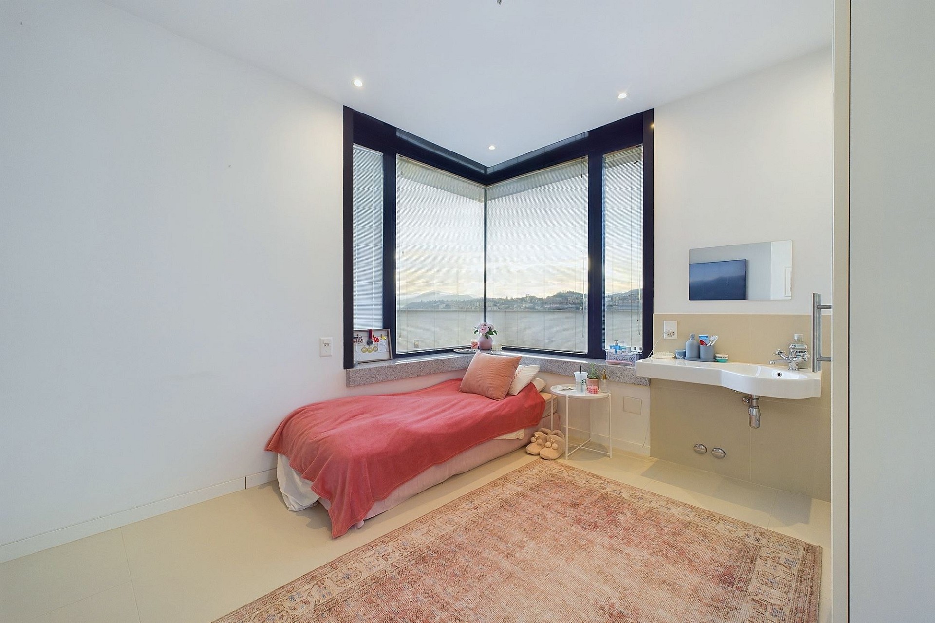 Helles Schlafzimmer mit Eckfenster und eingebautem Waschbereich