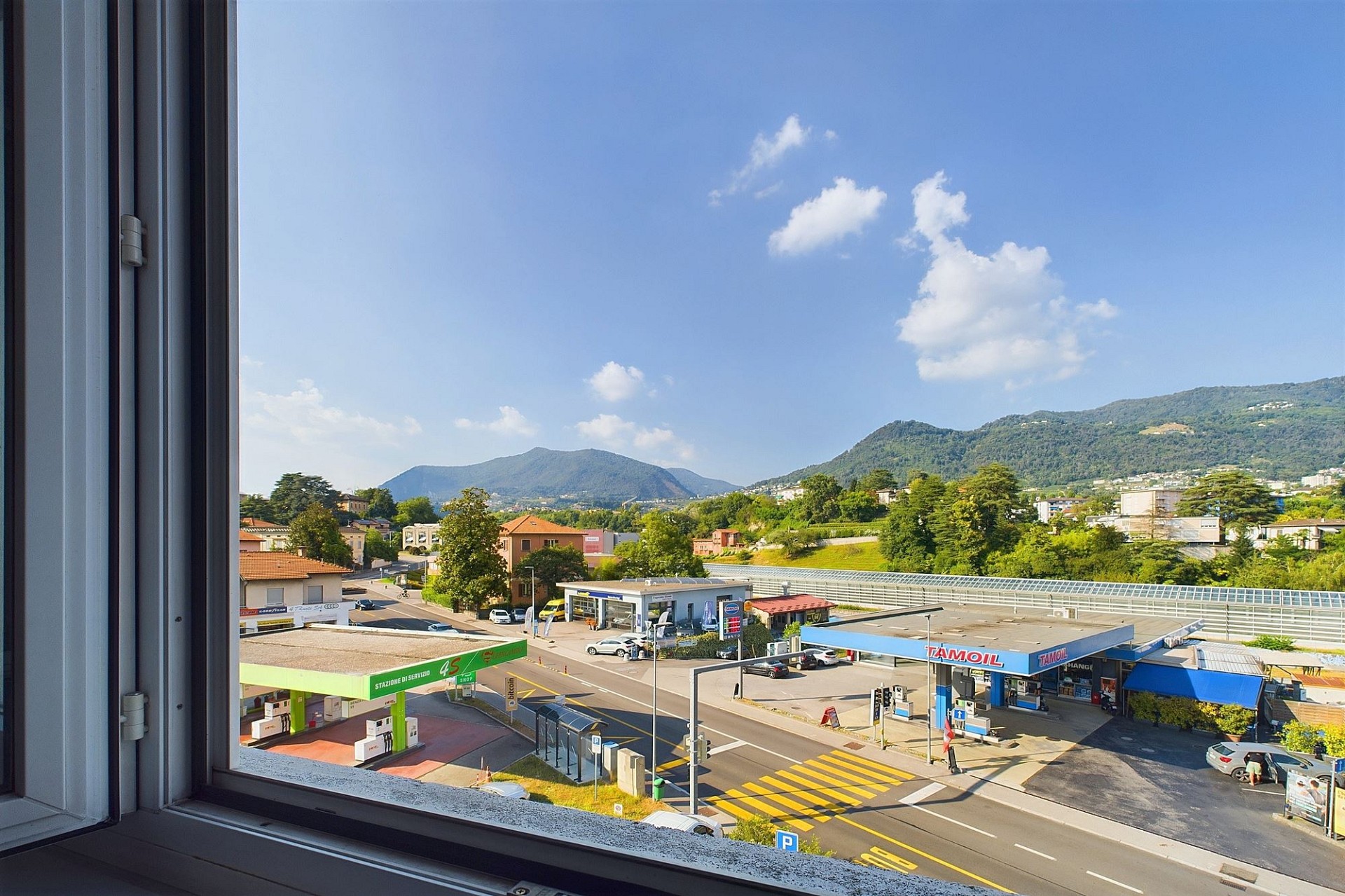 Ausblick aus einem Fenster auf Straße, Tankstelle und Berge