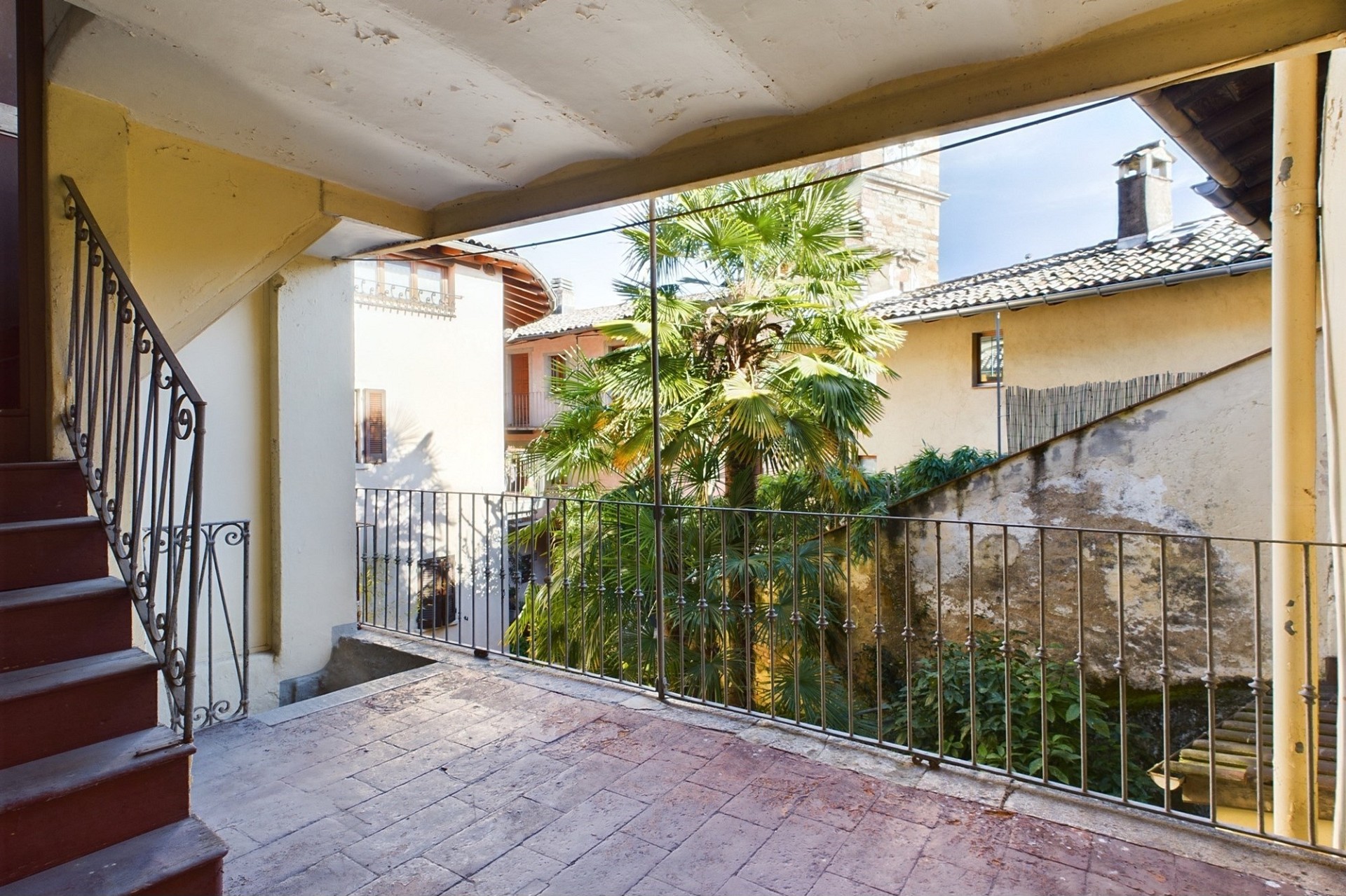 Überdachter Balkon mit Blick in einen begrünten Innenhof