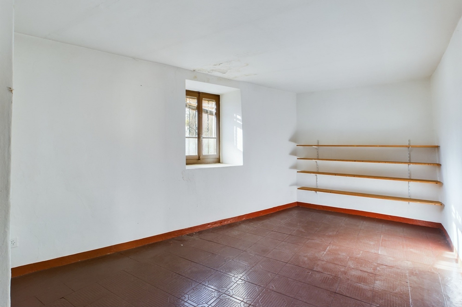 Leerer Raum mit kleiner Fensteröffnung und Wandregalen