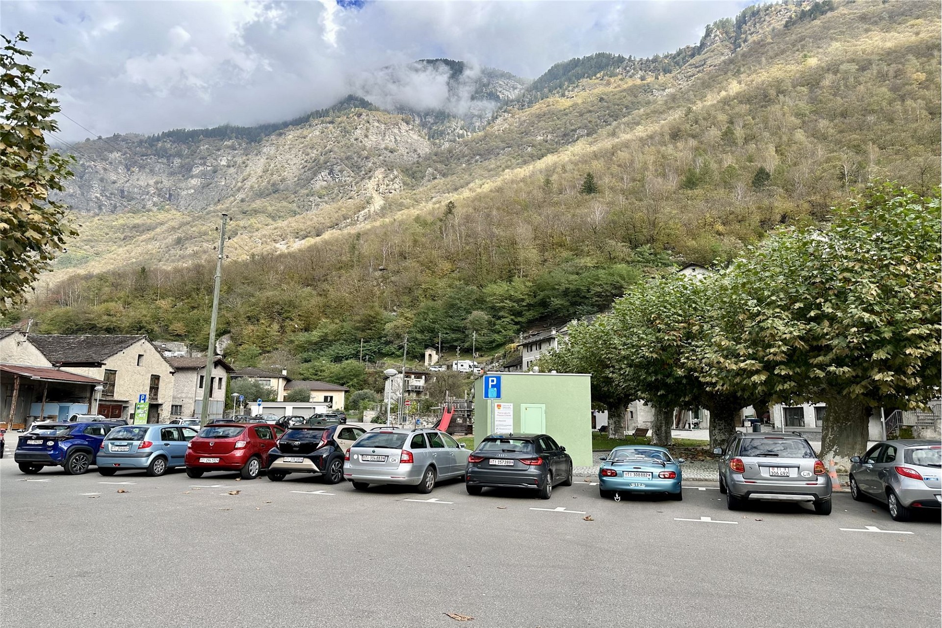 Bergdorf mit Parkplatz vor alpiner Hanglandschaft