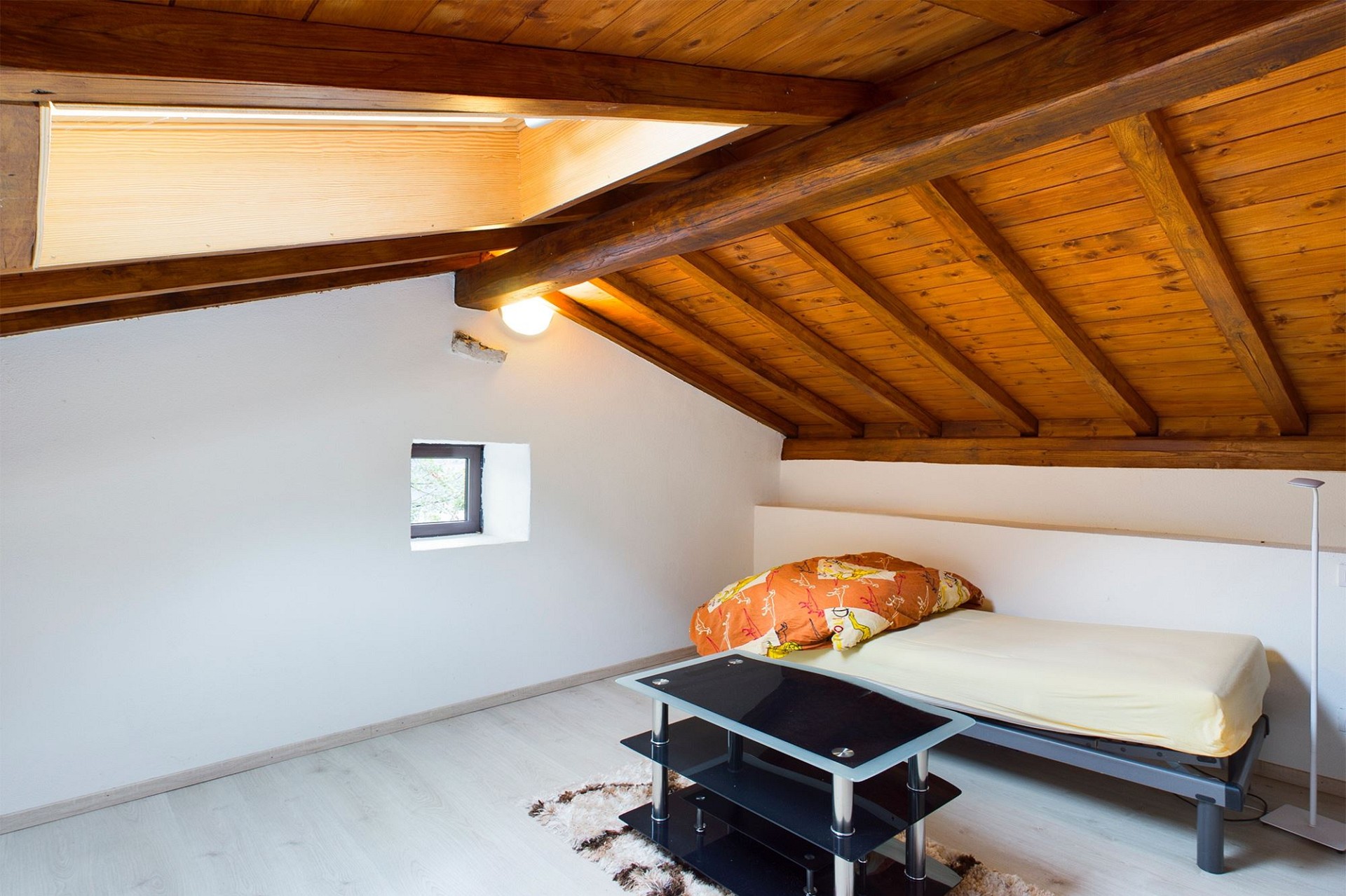 Dachgeschoss-Schlafzimmer mit sichtbaren Holzbalken