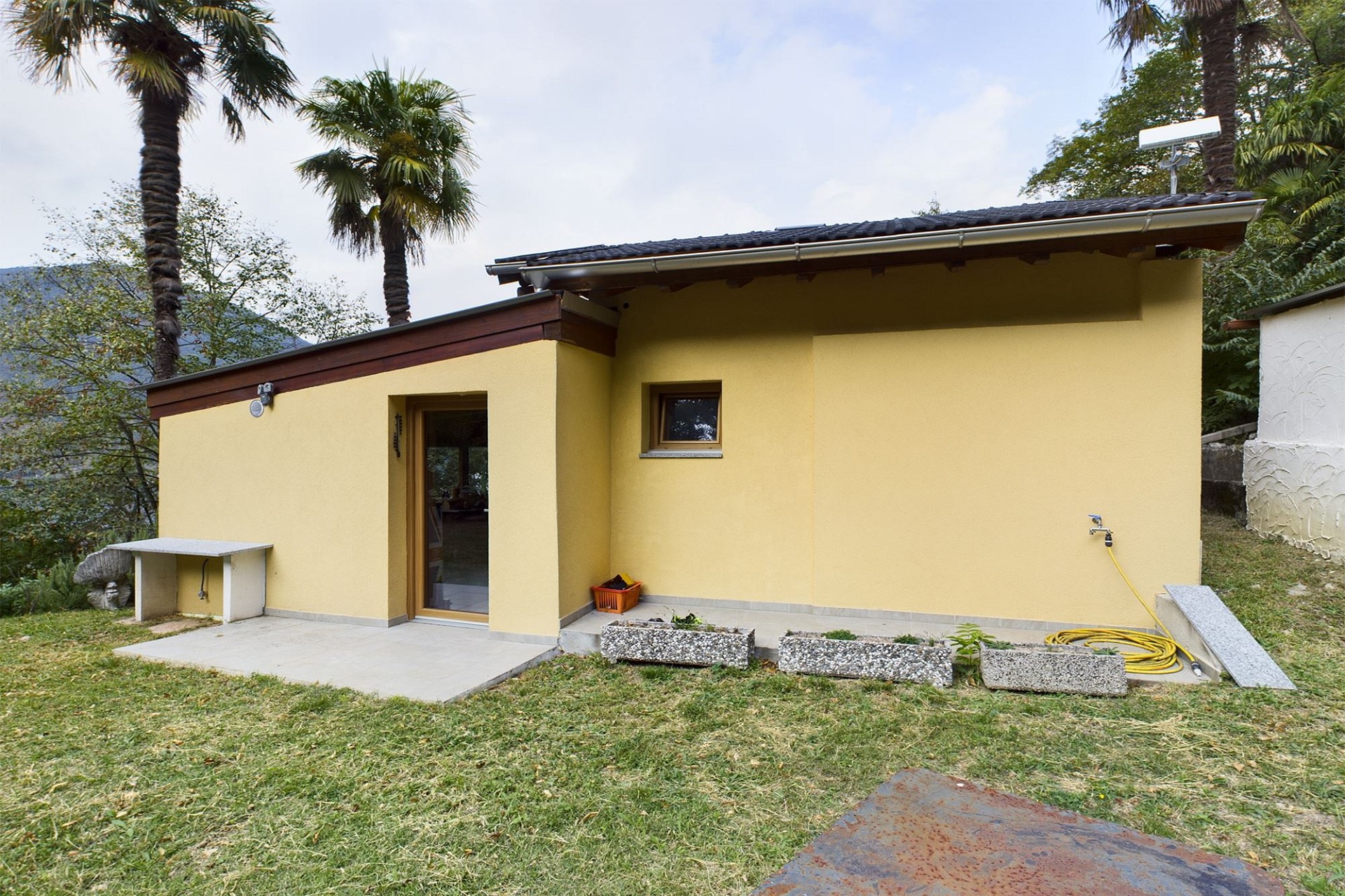 Kleines gelbes Gartenhaus mit Flachdach