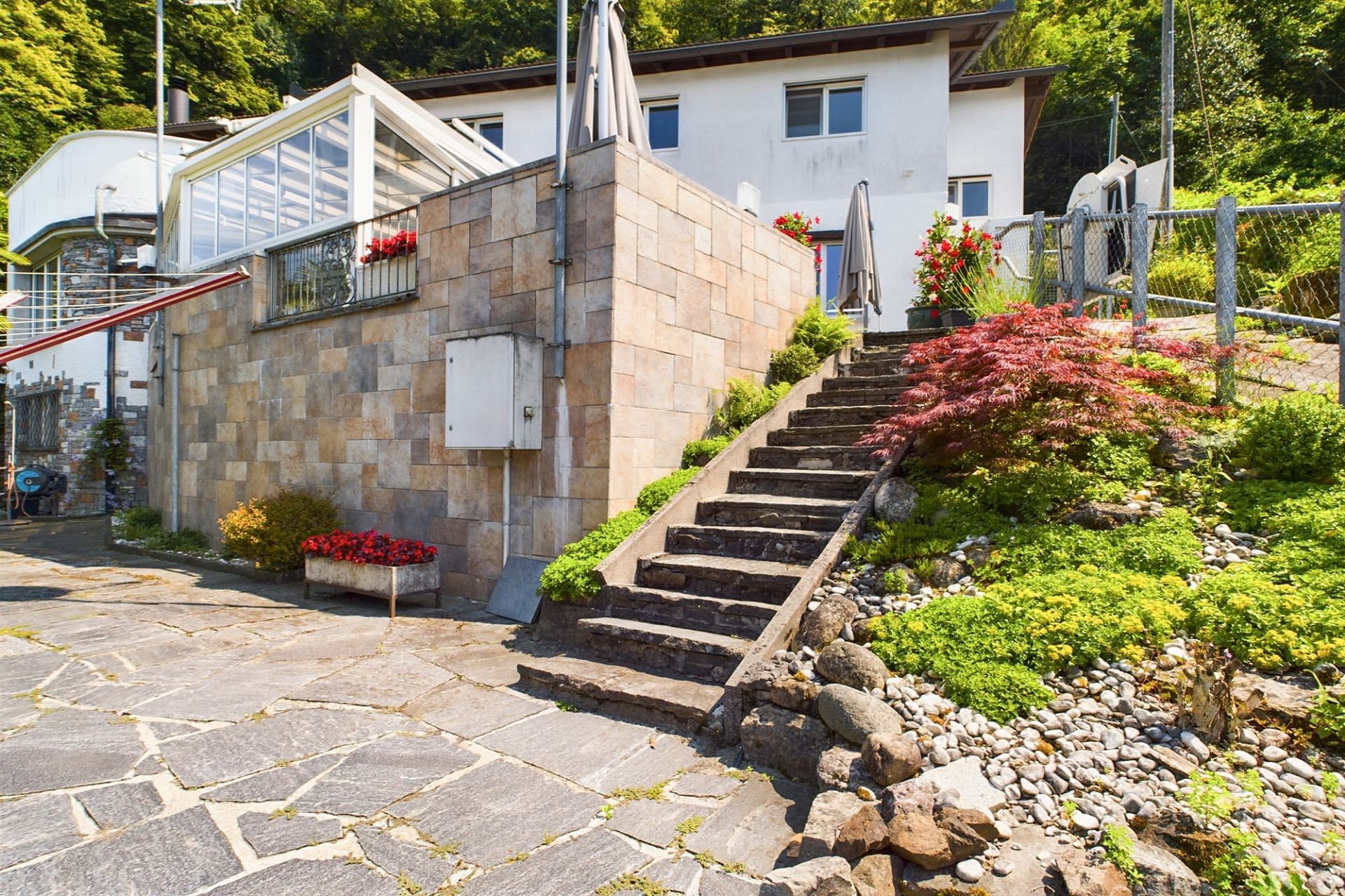 Außenansicht eines Hauses mit Steintreppe und Gartenhang