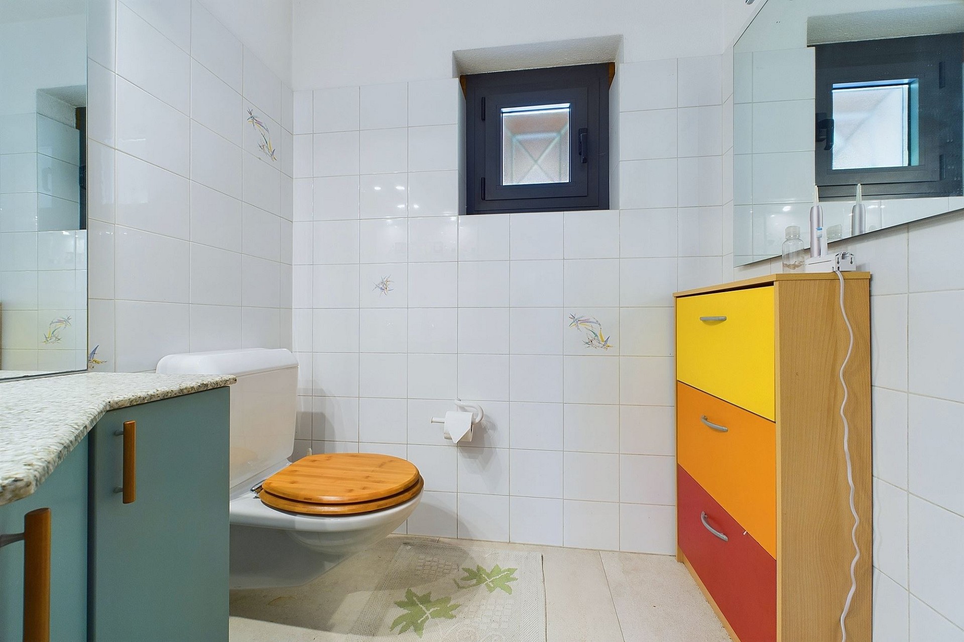 Badezimmer mit WC und farbigem Unterschrank