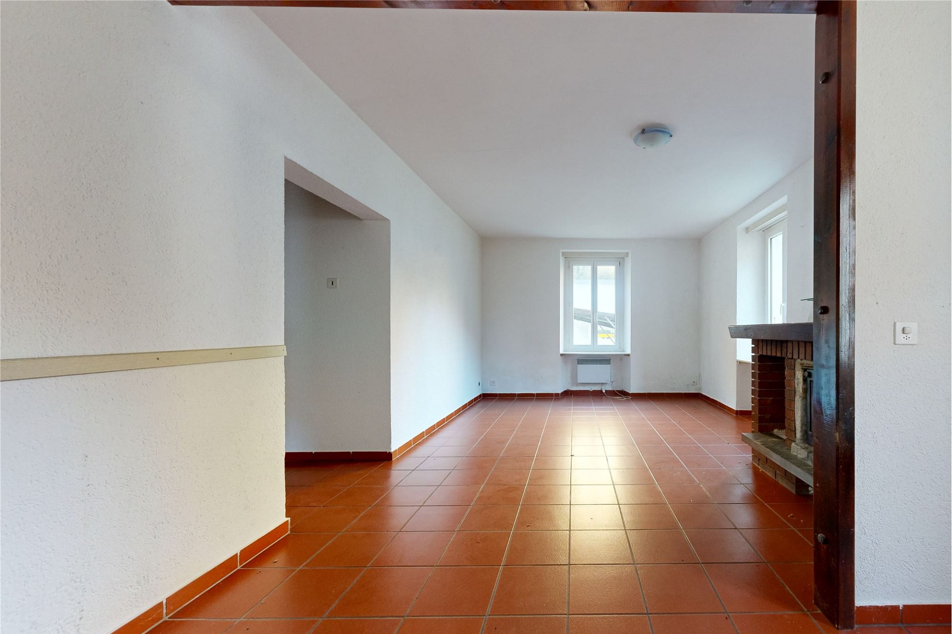 Heller Wohnraum mit Kamin und Terrakottafliesen