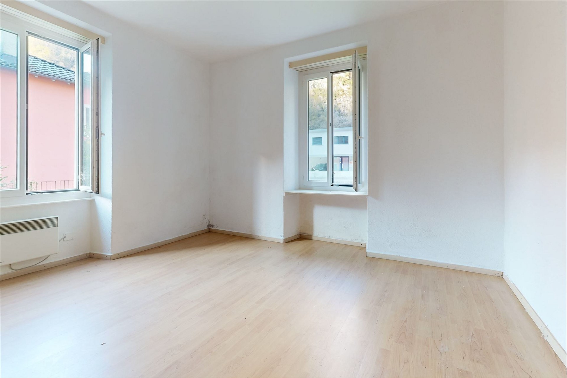 Helles, leeres Zimmer mit zwei Fenstern