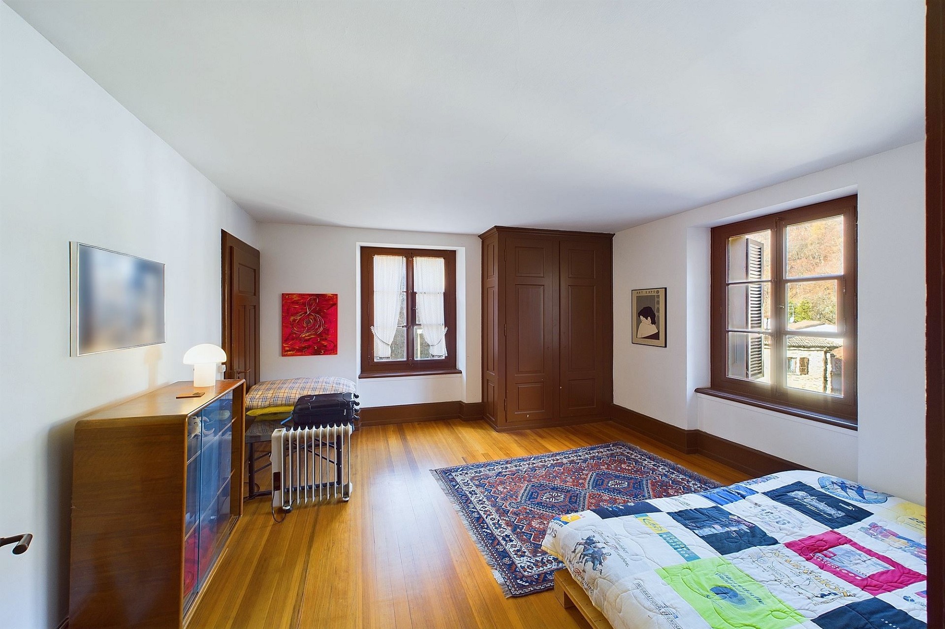 Schlafzimmer mit Holzboden und zwei Fenstern