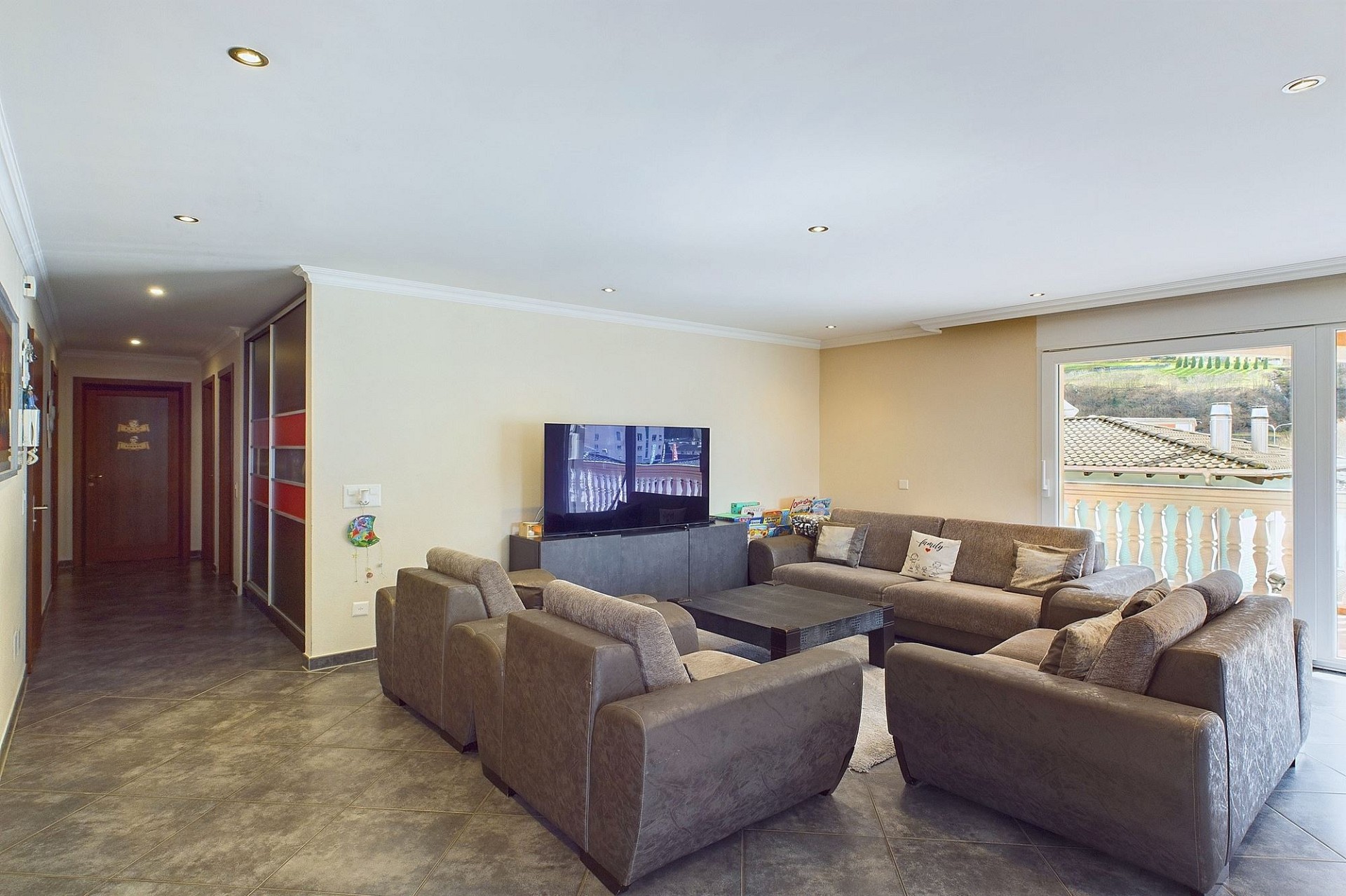 Großzügiges Wohnzimmer mit Fliesenboden und Balkonblick