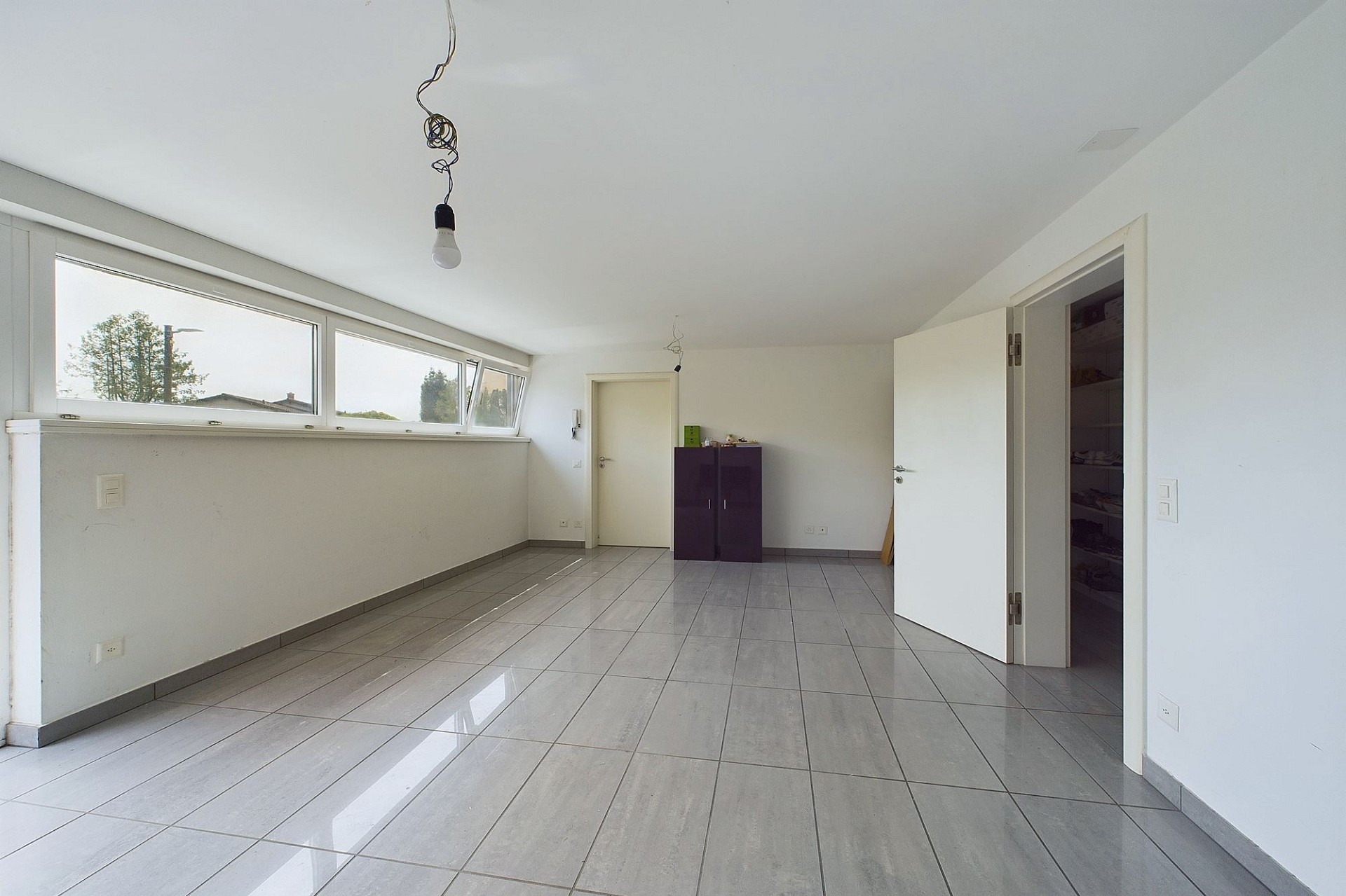 Heller, leerer Raum mit Fliesenboden und Fensterband
