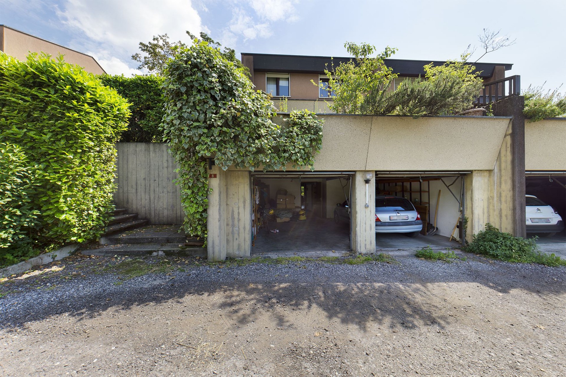 Garagenzeile mit Zufahrt und begrüntem Wohnhaus